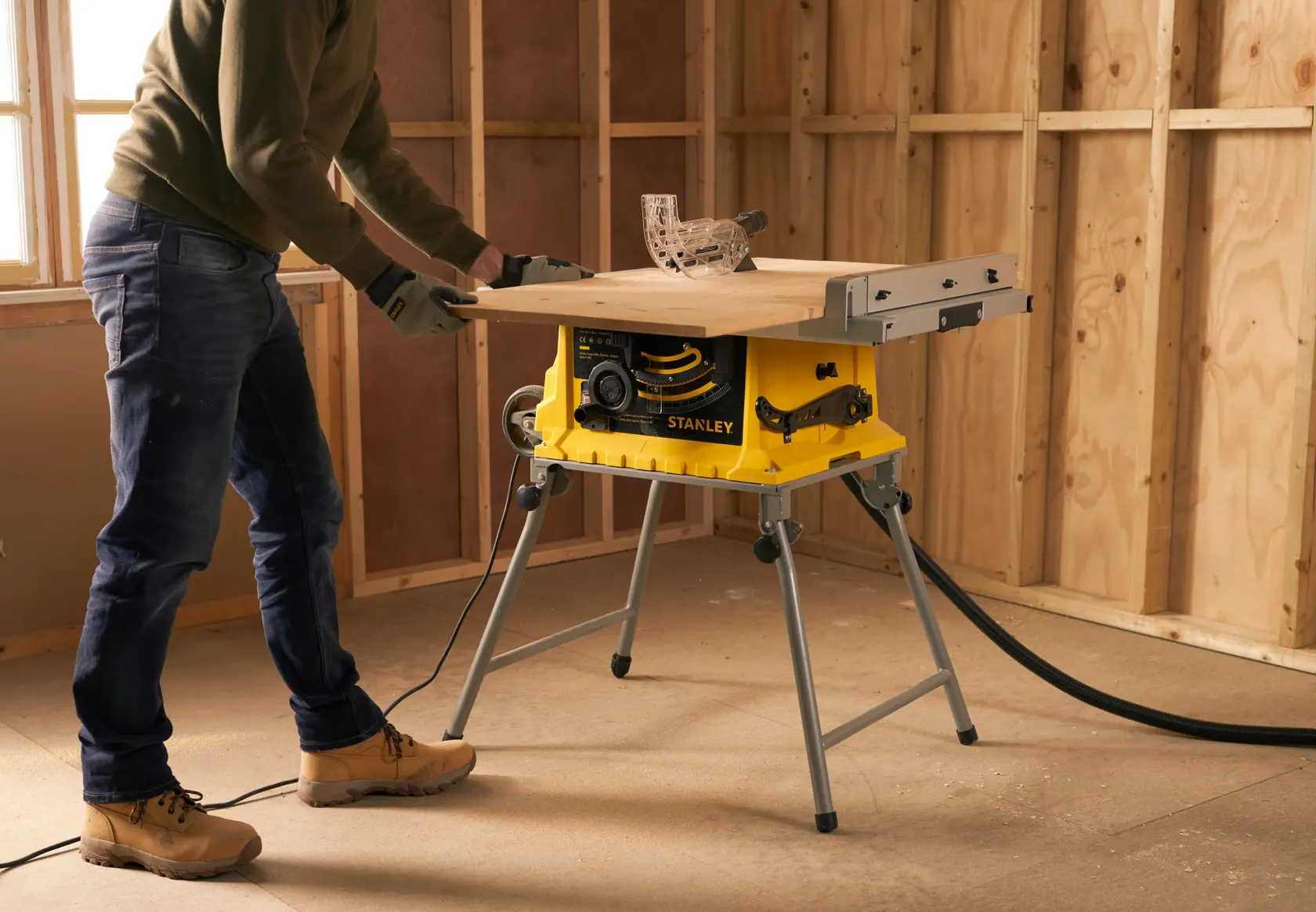 Scie sur table STANLEY SST1800 utilisée sur un chantier, base jaune, surface de travail étendue, coupe du bois en cours.