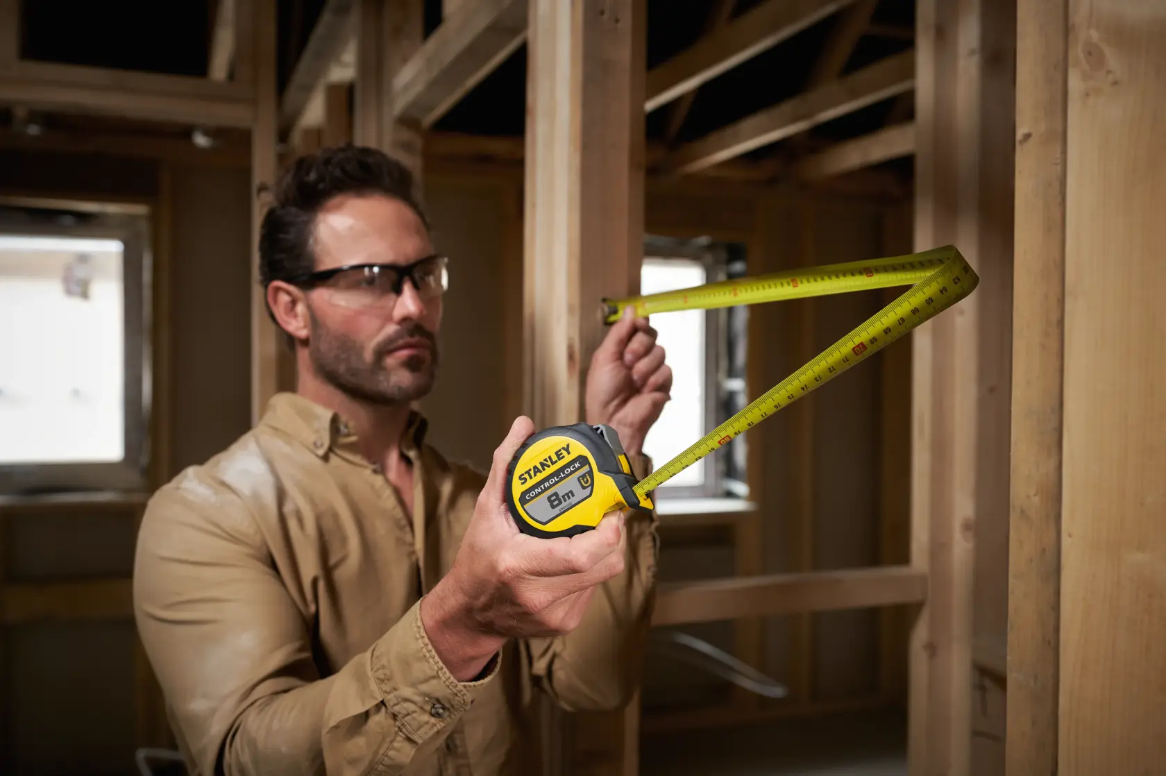 Stanley STHT37232-0 mètre ruban utilisé pour mesurer un cadre en bois, boîtier jaune et noir.