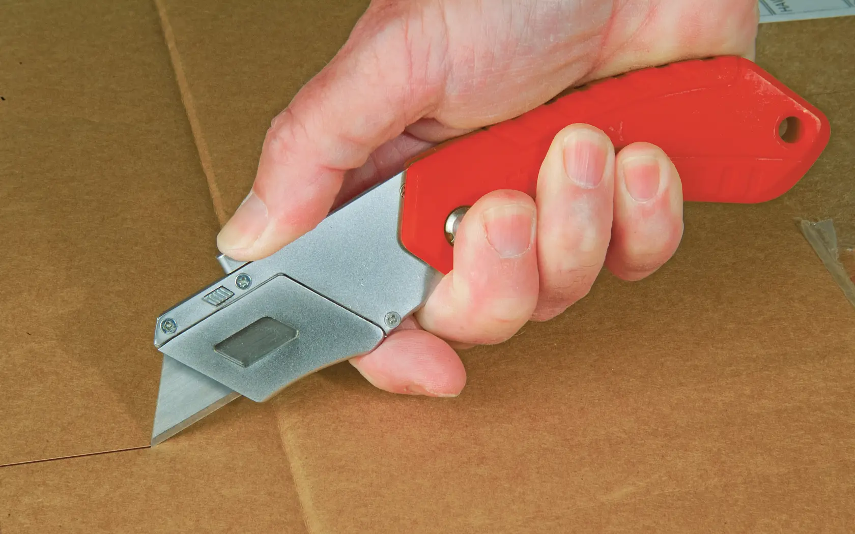 STANLEY 0-10-243 couteau pliant utilitaire à poignée rouge coupant du carton, photo en gros plan.