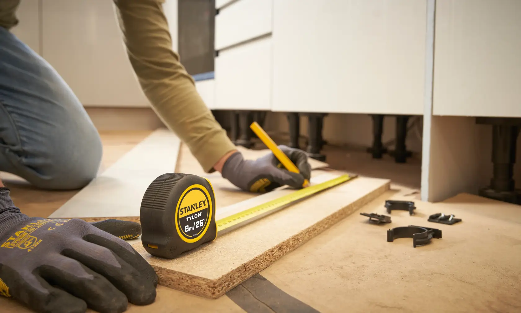 STANLEY 0-30-656 tape measure in use, measuring wood board, close-up indoor workshop scene.