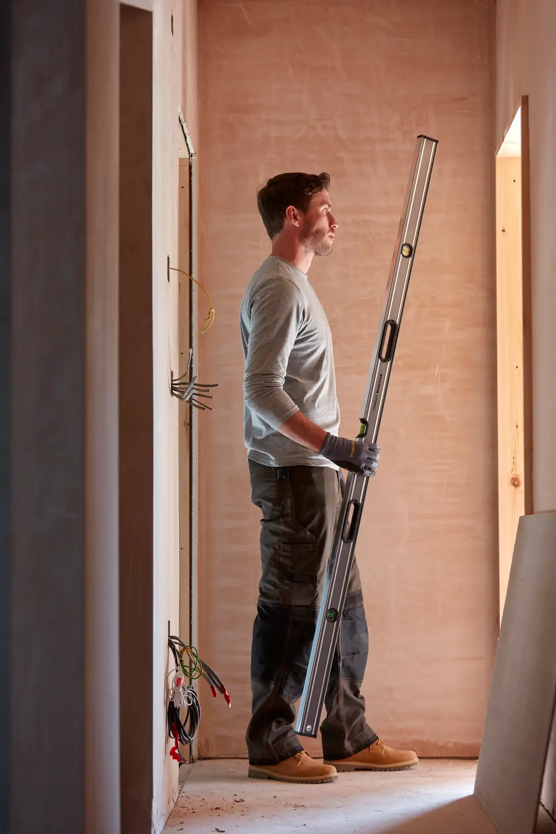 STANLEY 0-43-672 spirit level held by person in construction setting, vertical indoor view.