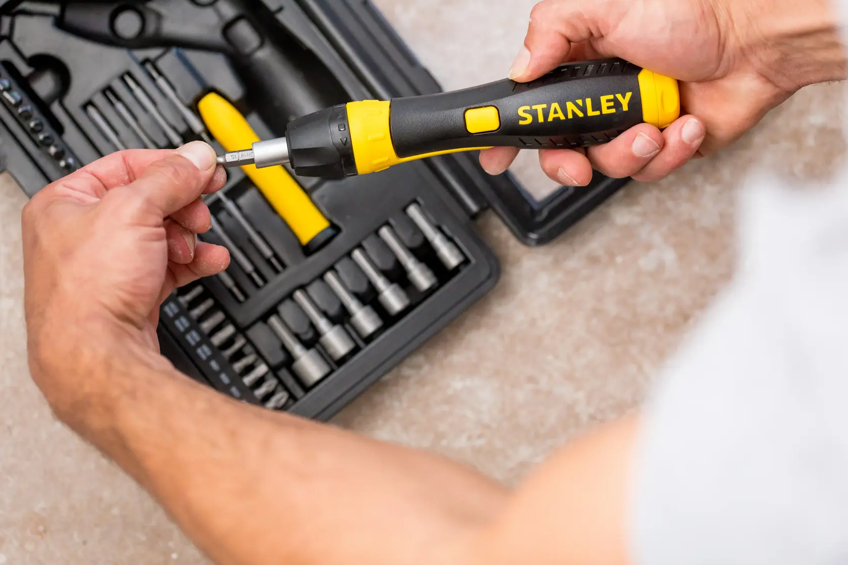 STANLEY 0-63-038 Ratschen-Schraubendreher-Set mit schwarz-gelbem Griff, Person setzt Bit ein, Draufsicht.