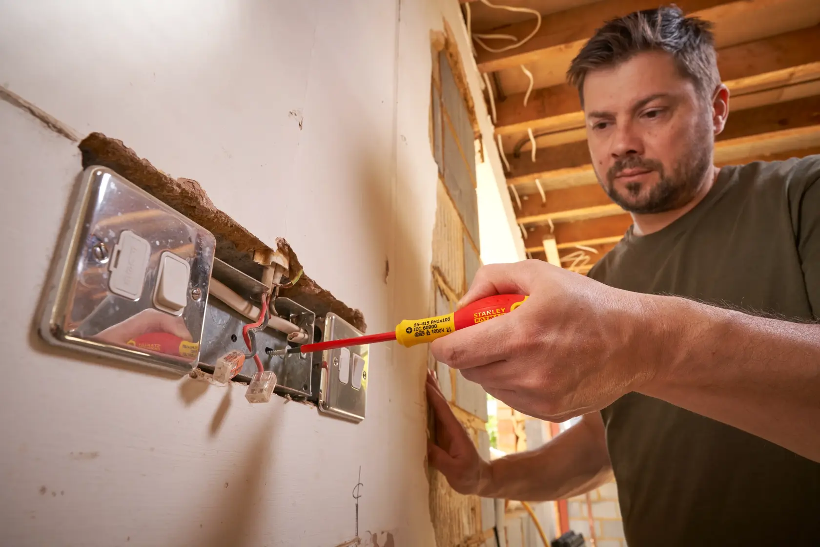 Photo of STANLEY 0-65-415 insulated screwdriver used on an electrical outlet during indoor wiring work.