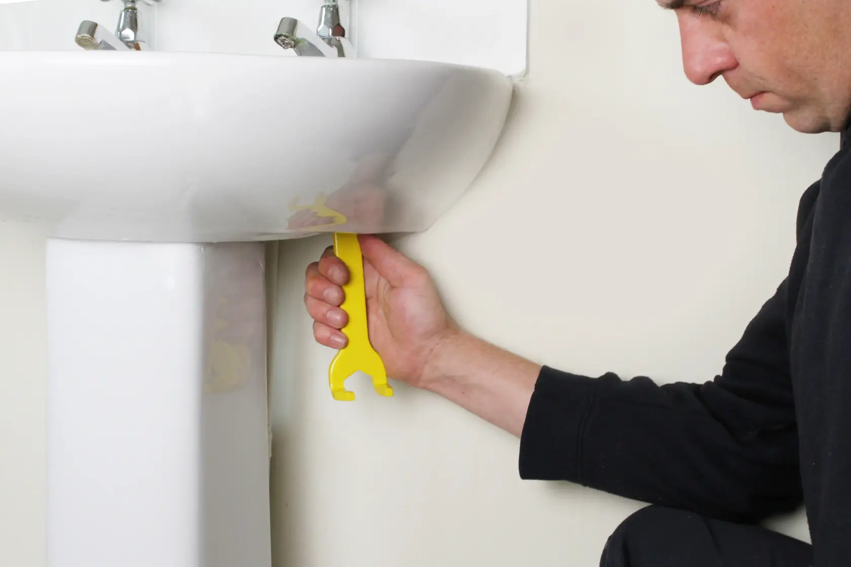 STANLEY 0-70-454 yellow plastic basin wrench in use for tightening under sink.
