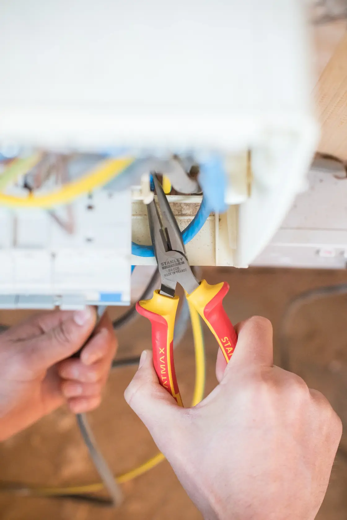 Photo of STANLEY 0-84-006 insulated long nose pliers with red and yellow handles used to grip electrical wire.