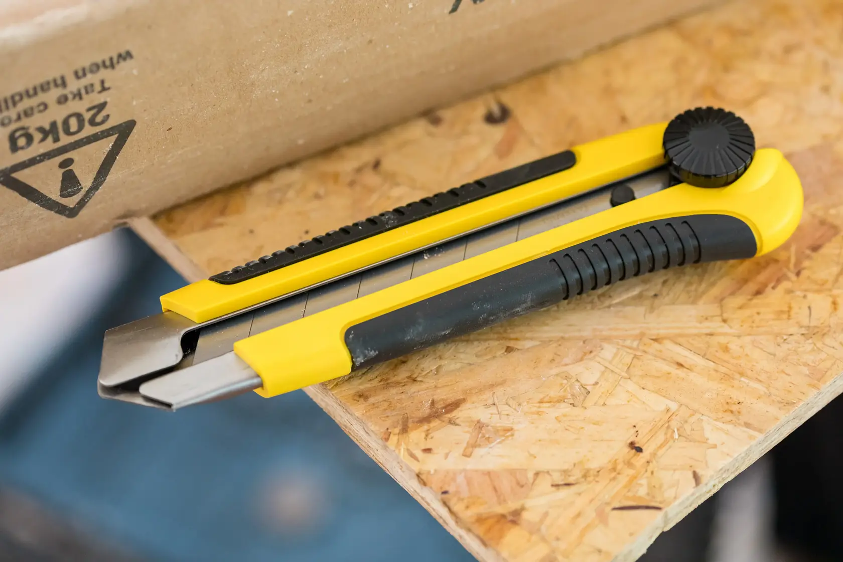 STANLEY 1-10-425 couteau utilitaire jaune et noir sur une surface en bois, vue latérale en angle.