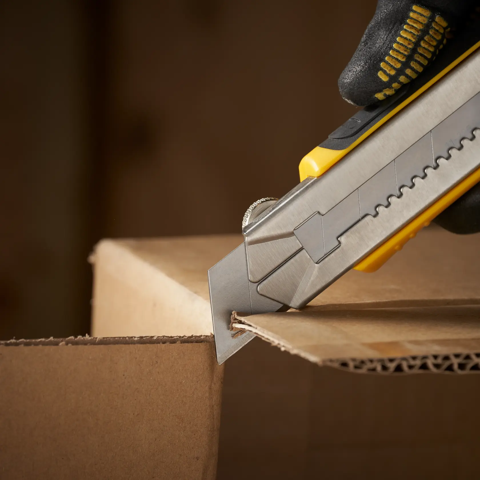 STANLEY 1-11-325 utility knife cutting cardboard box, close-up side angle, photography.