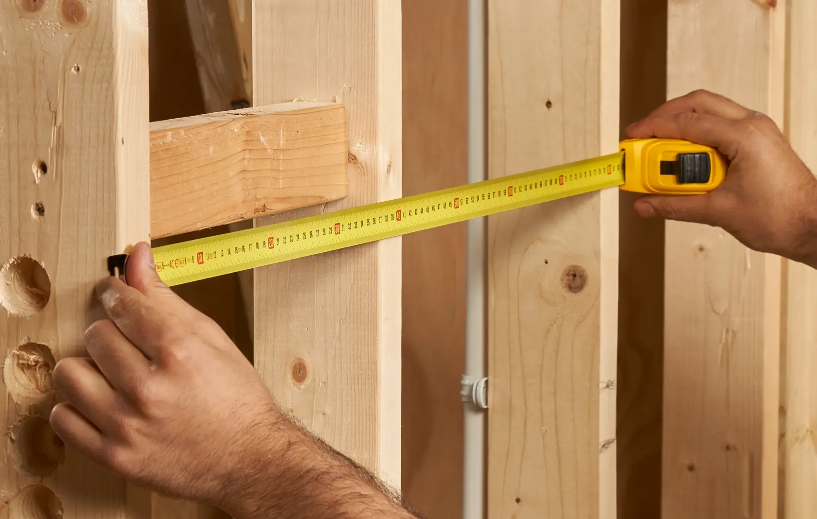 Photo of STANLEY 1-30-457 tape measure being used to measure wooden studs, front angle.