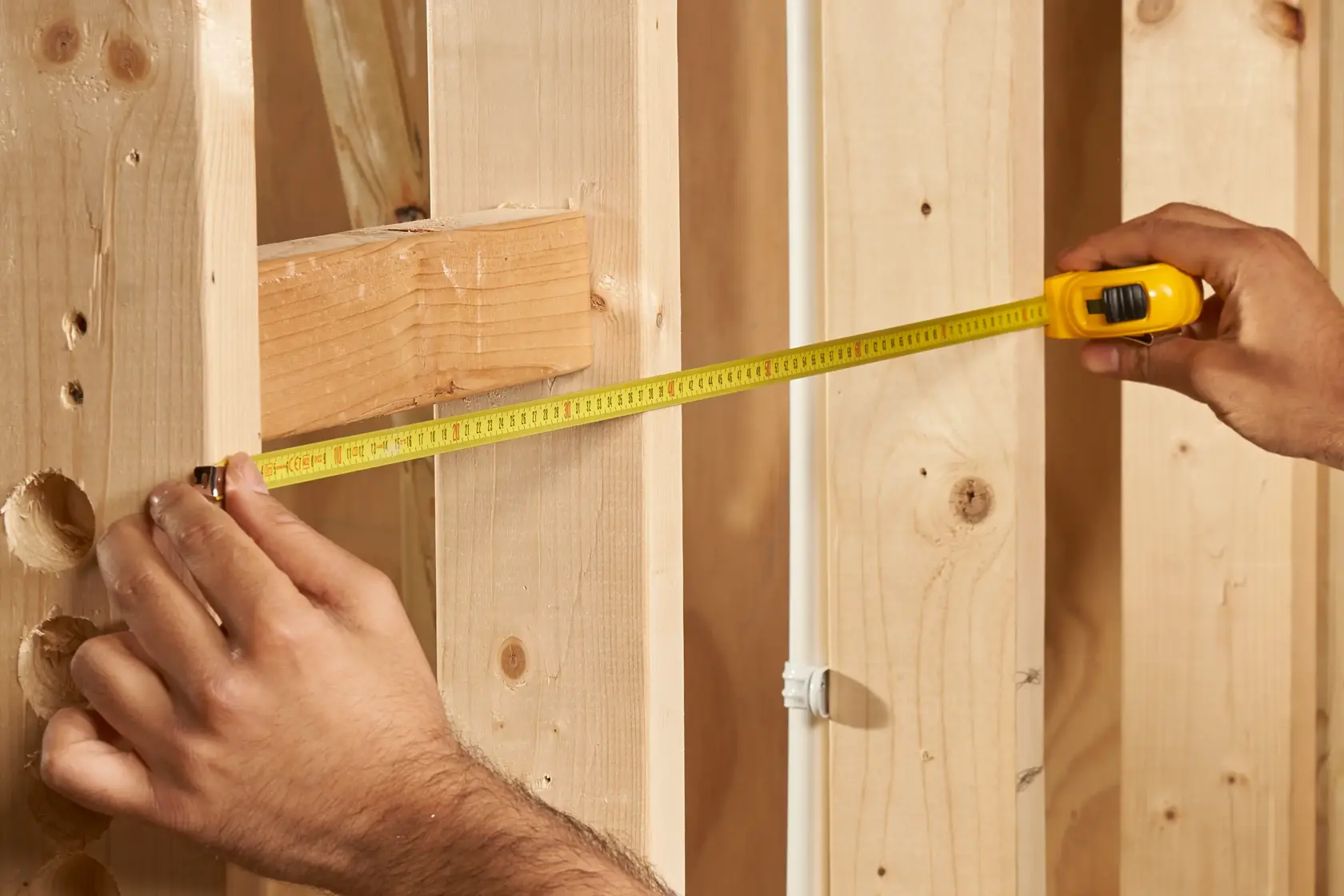 STANLEY 1-30-487 tape measure extended across wooden studs, close-up photo of tool in use.