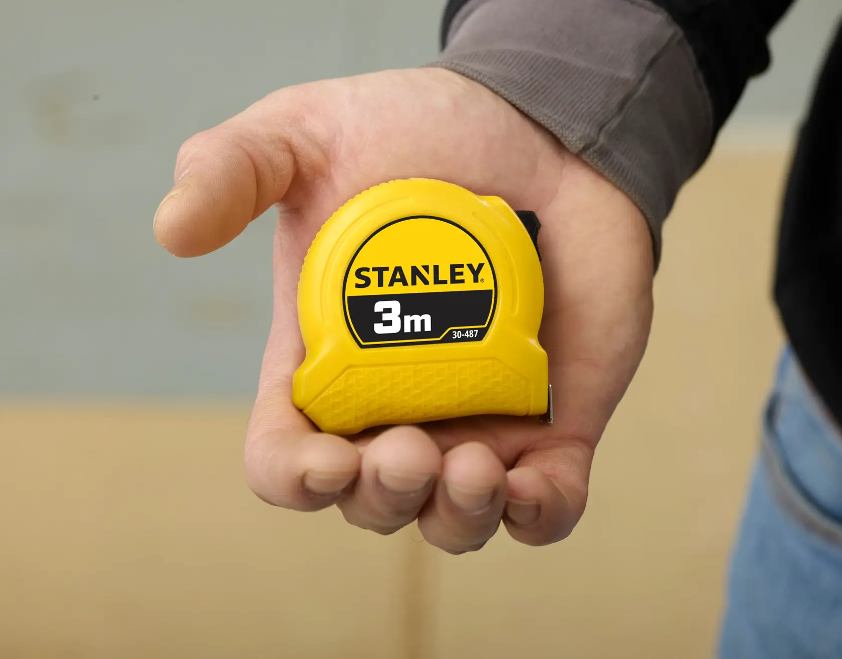 Photo of STANLEY 1-30-487 yellow 3m tape measure held in a hand, compact plastic design.