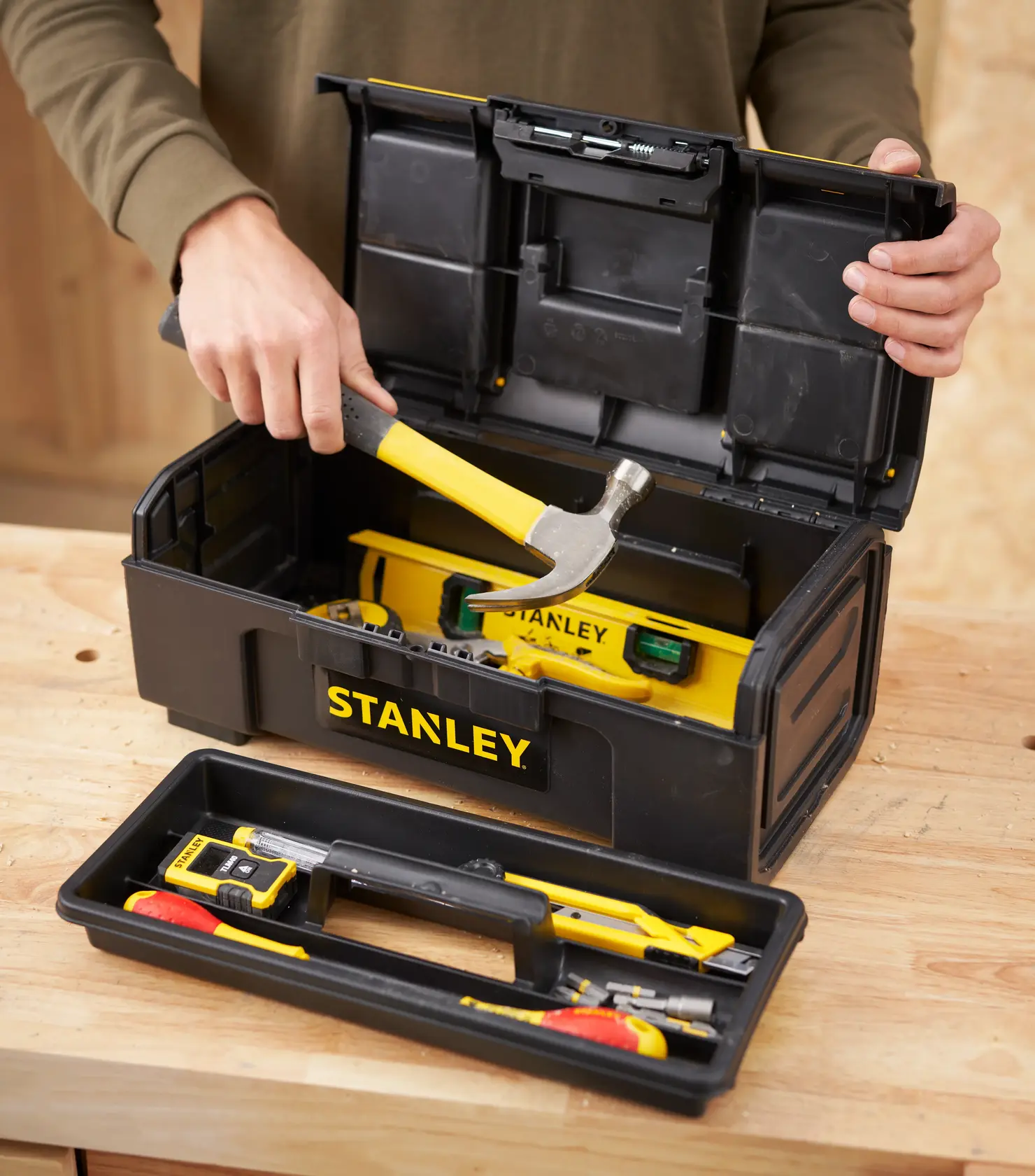 Photo de boîte à outils STANLEY 1-79-216 ouverte avec outils jaunes, personne tenant un marteau.