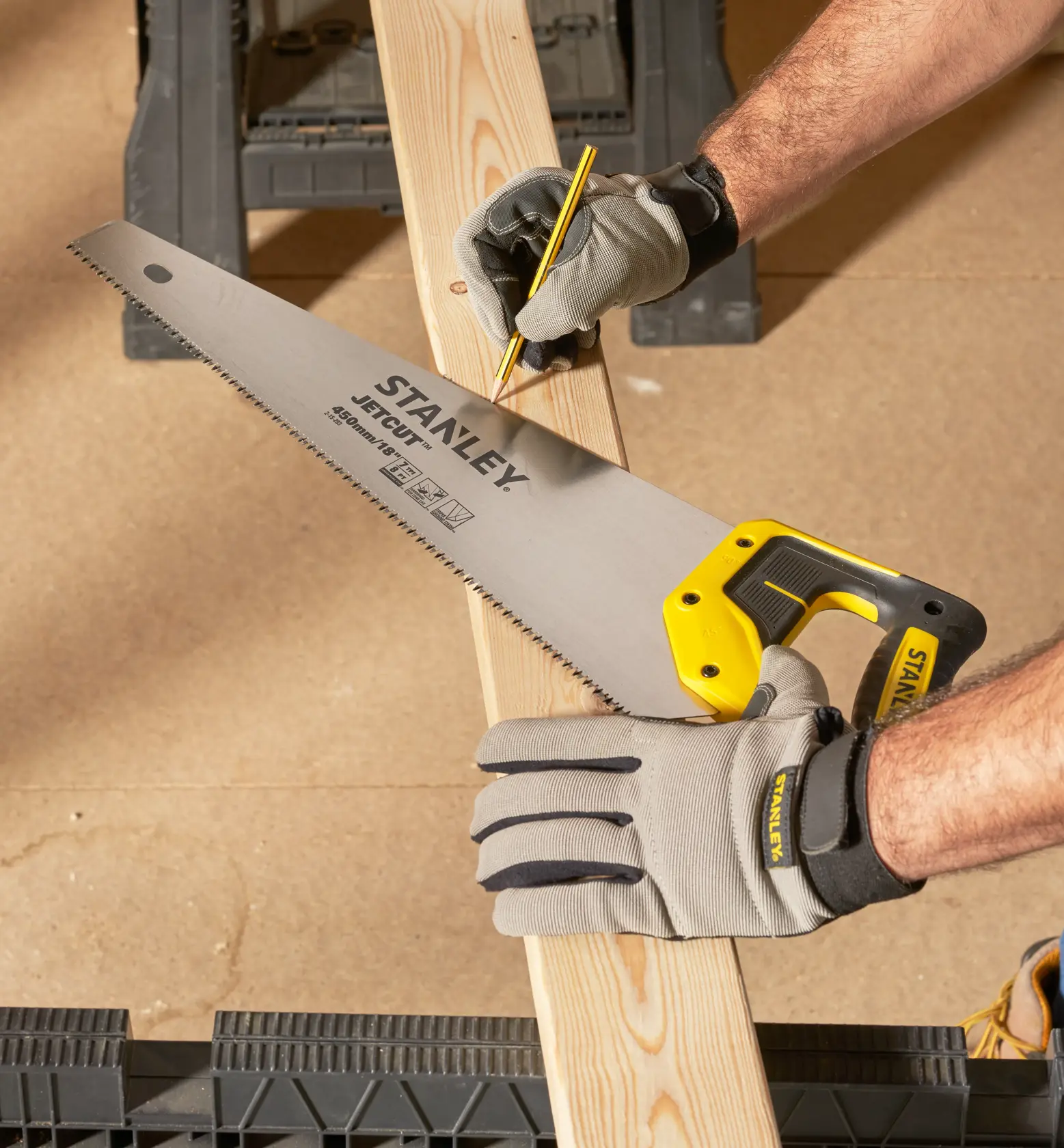 STANLEY 2-15-283 Handsäge mit gelbem Griff, von behandschuhter Hand gehalten, Markierung auf Holzbrett.