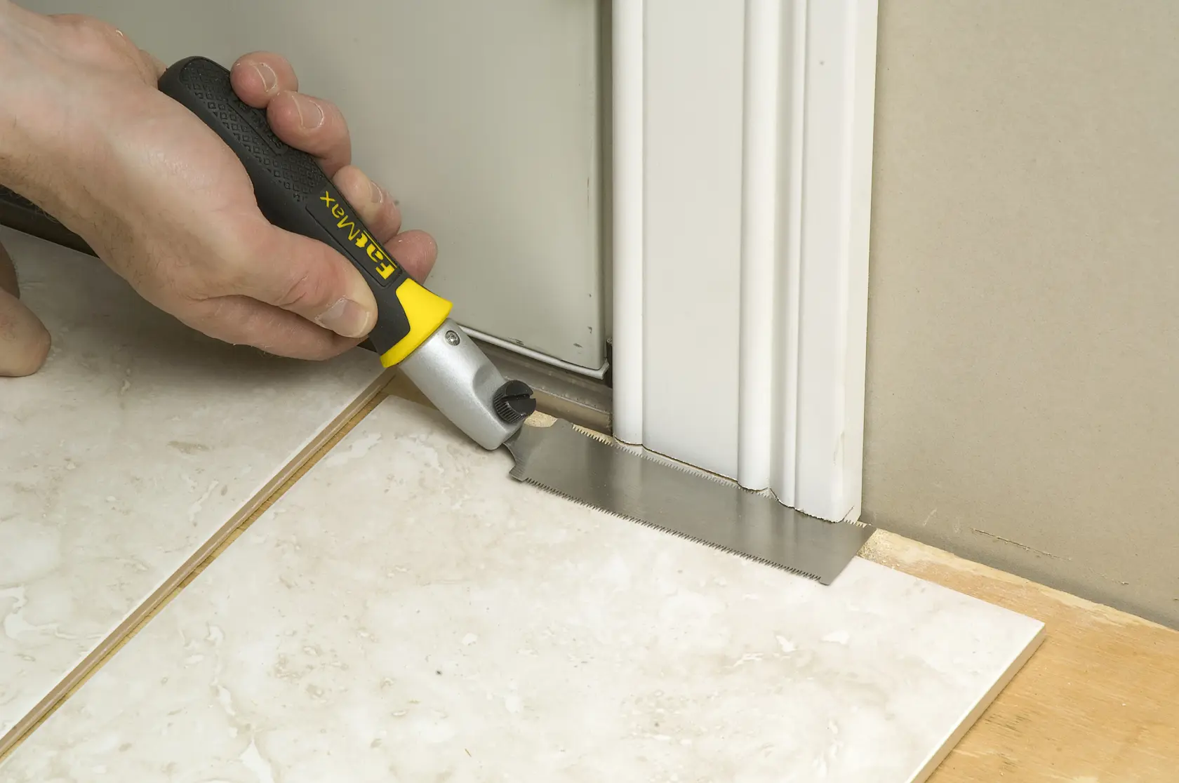 STANLEY 3-20-331 hand saw with black and yellow handle cutting door frame near floor, close-up view.