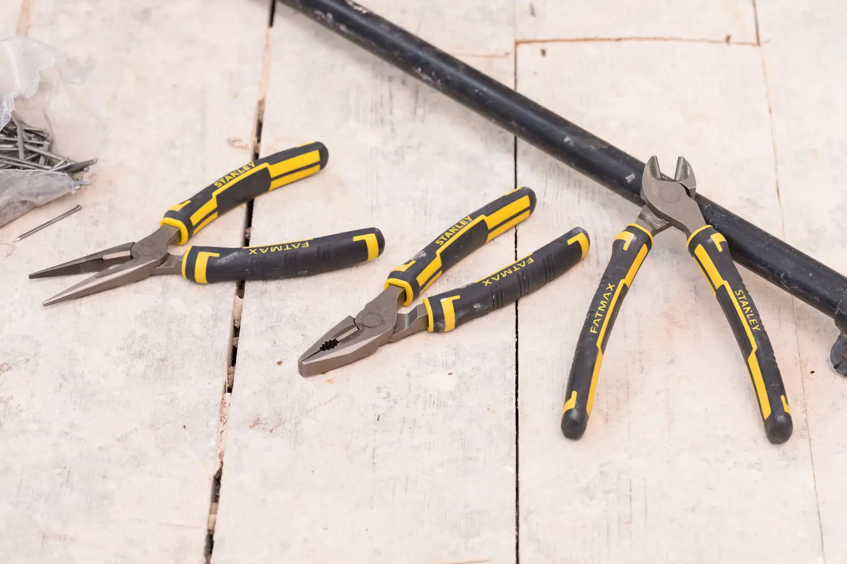 STANLEY 4-84-488 photography of three pliers with black and yellow handles on a wooden surface.