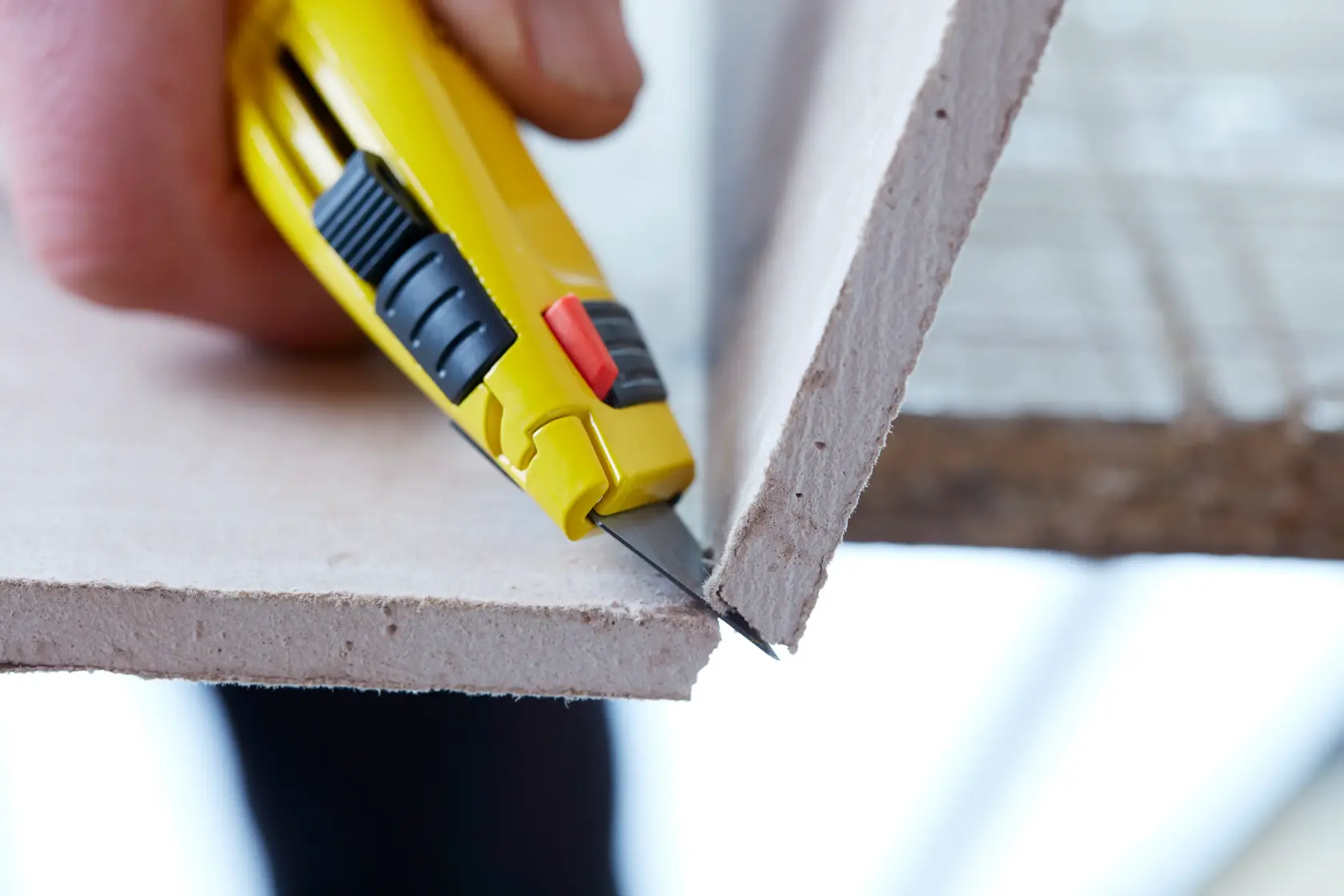 STANLEY 8-11-800 utility knife cutting drywall, close-up side angle.