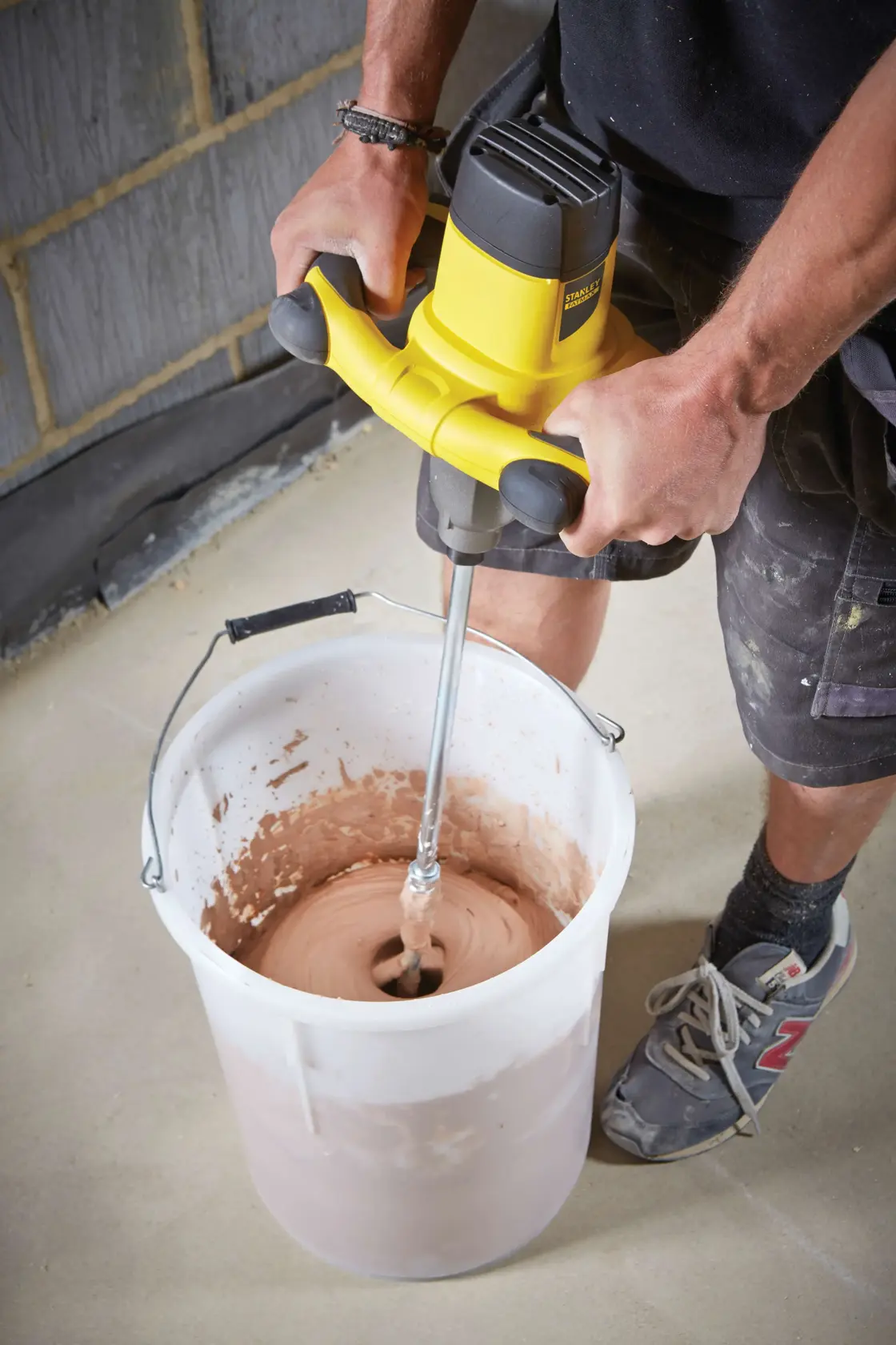 STANLEY FME190-QS miscelatore utilizzato per mescolare materiale in un grande secchio bianco in cantiere.