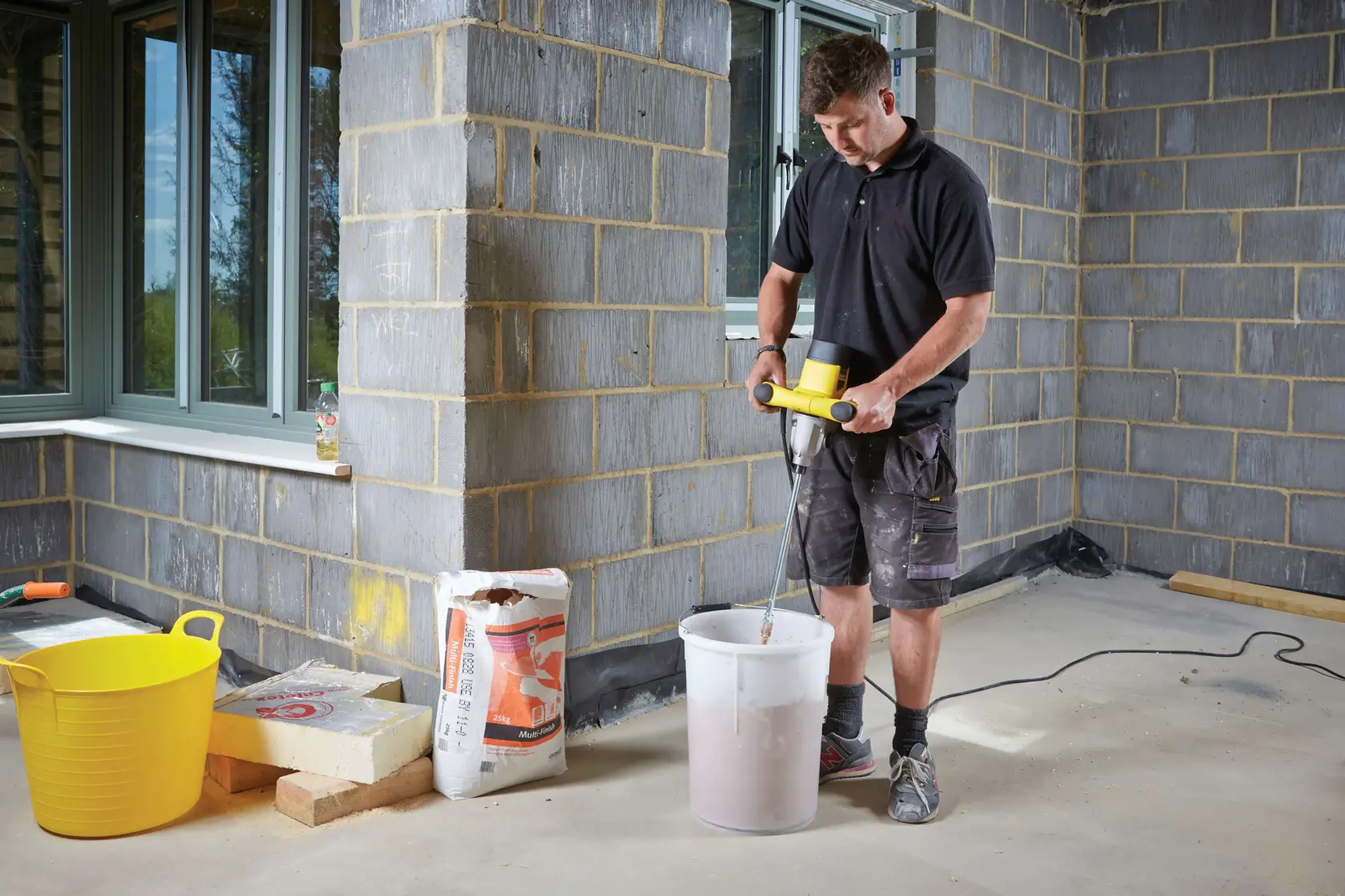 STANLEY FME190-QS mélangeur à palette utilisé pour mélanger des matériaux dans un seau blanc sur chantier.