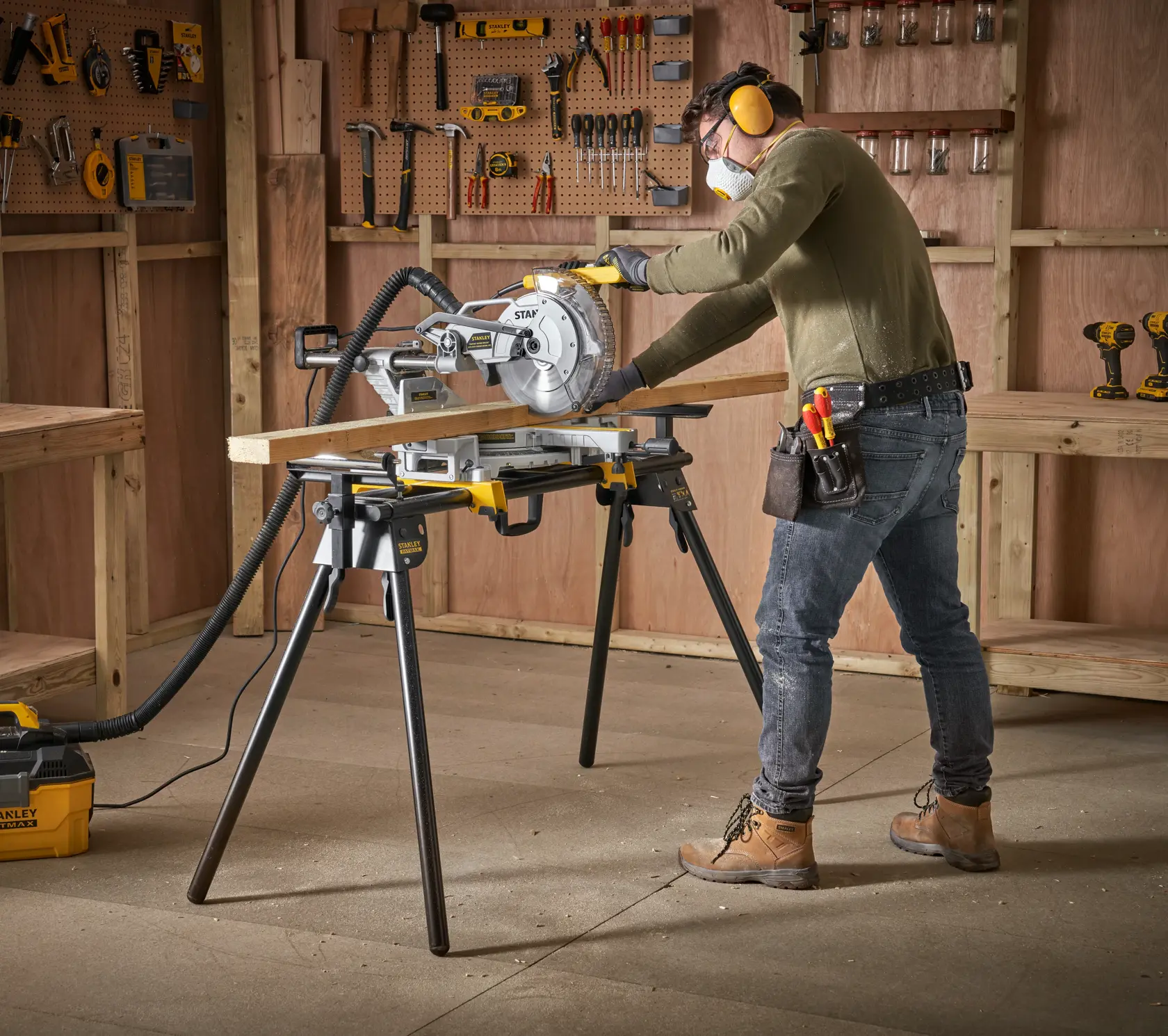Photo of STANLEY FME790-XJ miter saw on stand in workshop, worker cutting wood board.