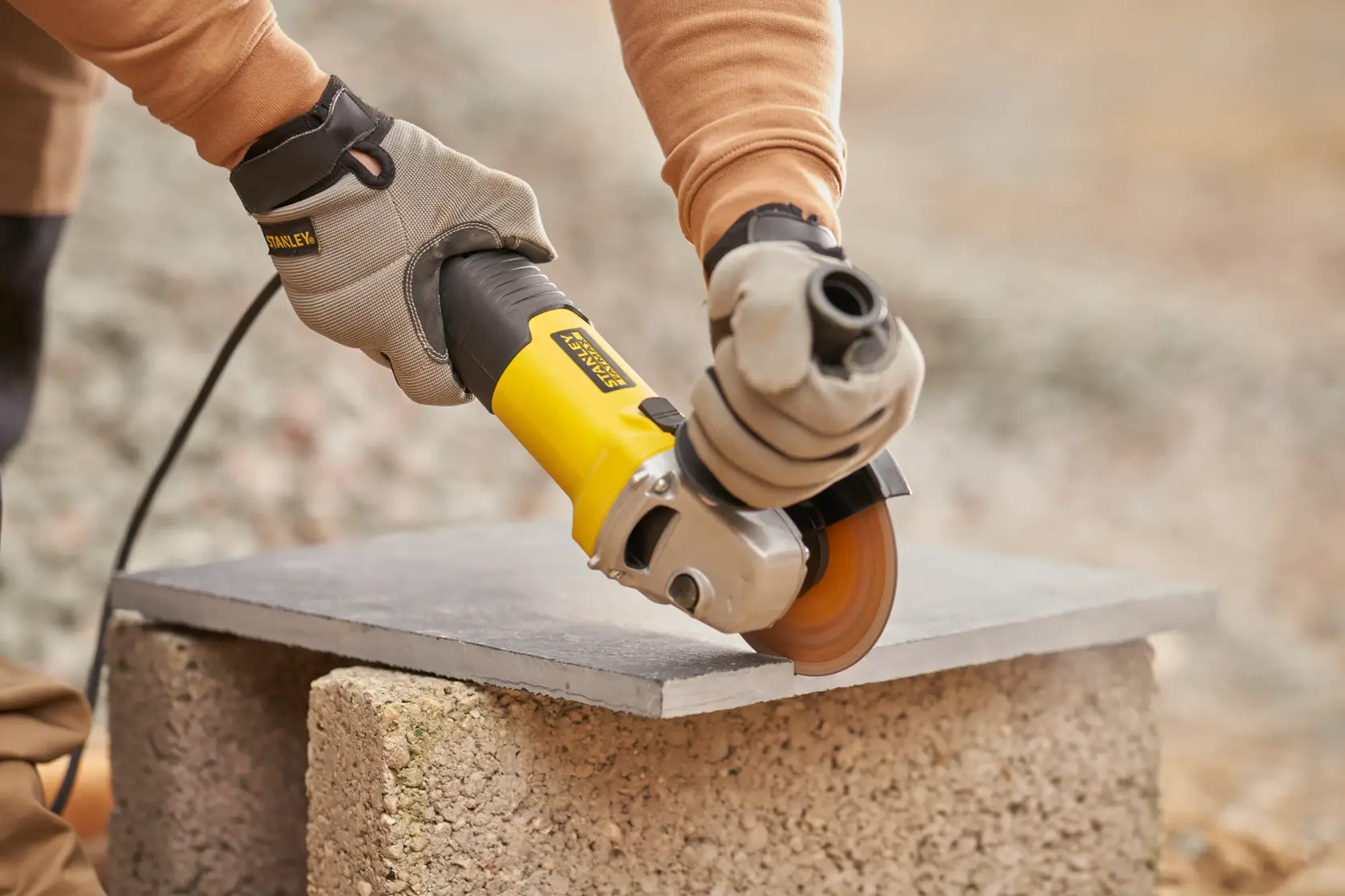 Stanley Fatmax angle grinder with yellow and black body and side handle, shown isolated on white background.