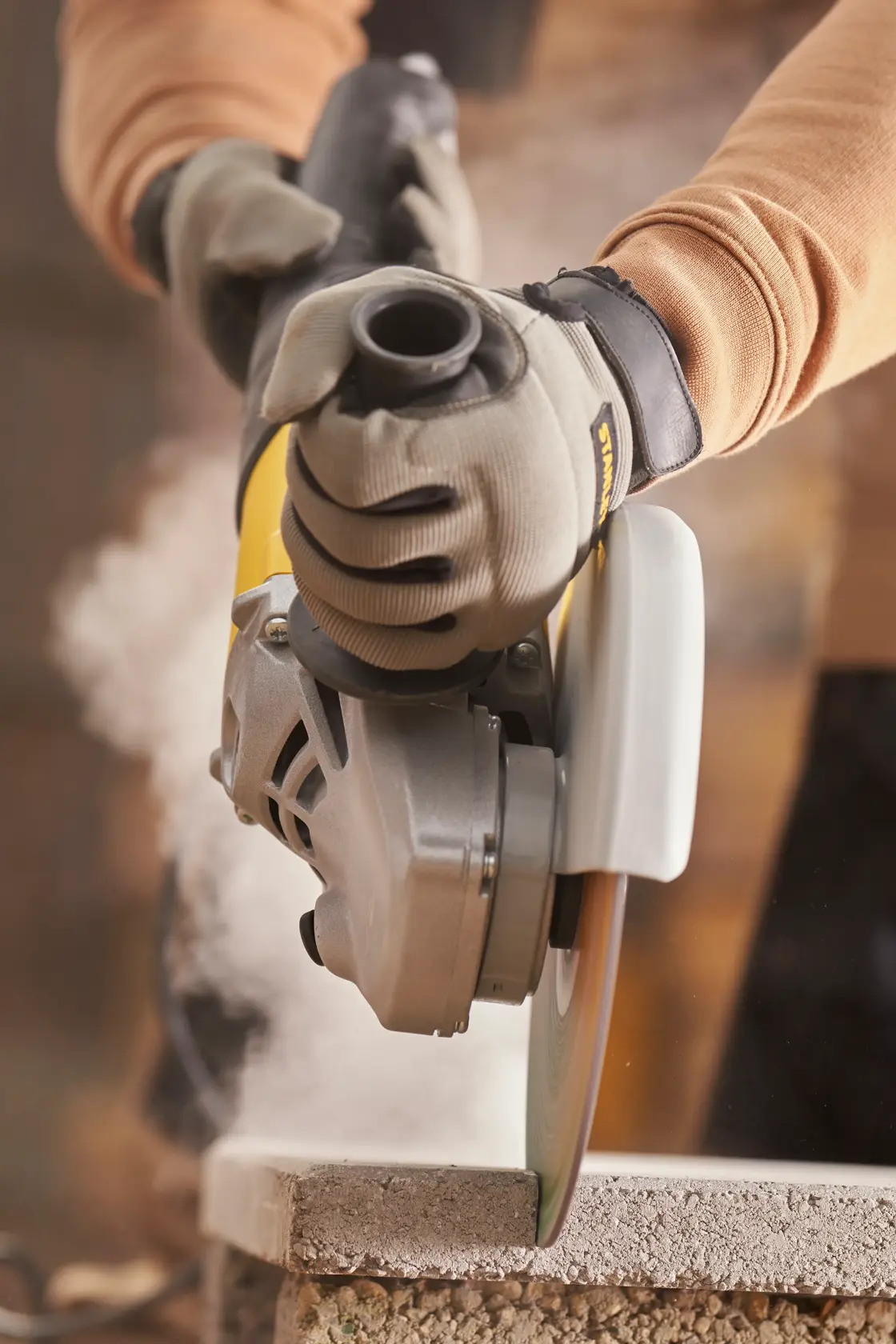 Stanley Fatmax angle grinder with yellow and black body and side handle, connected by a power cord.