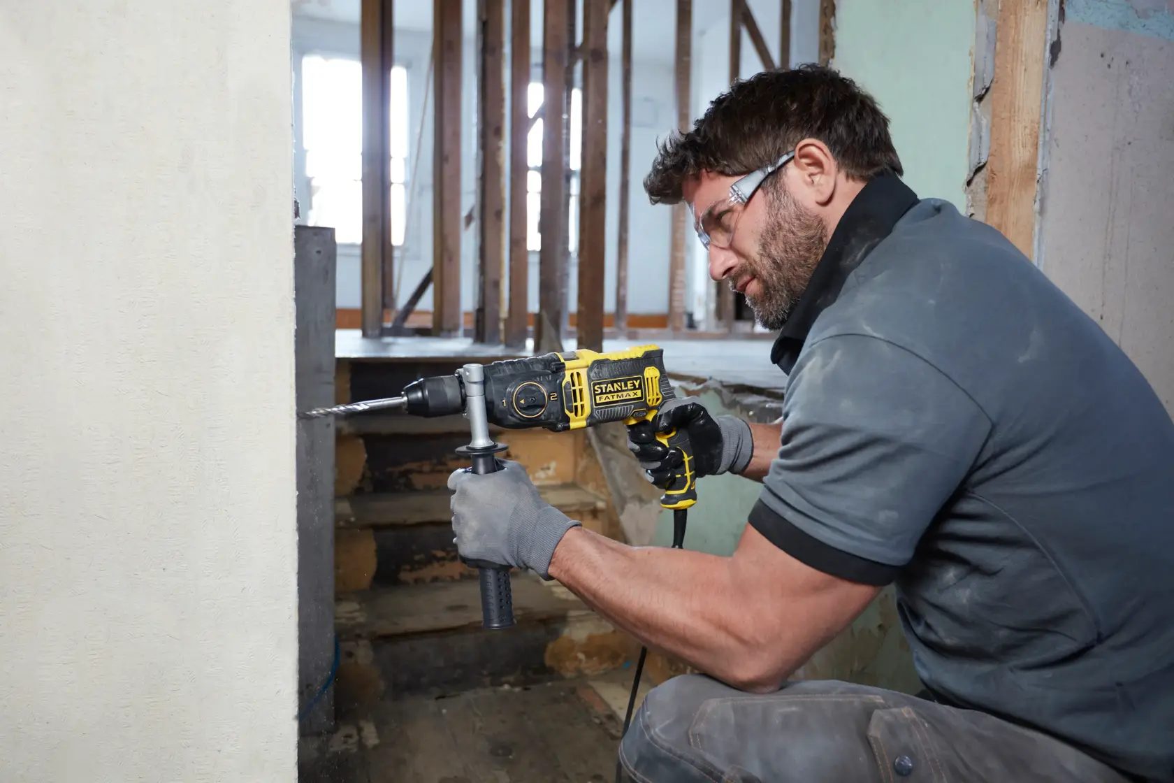 Foto des gelb-schwarzen STANLEY FMEH1100K Schlagbohrers im Einsatz beim Bohren in eine Wand bei Renovierung.