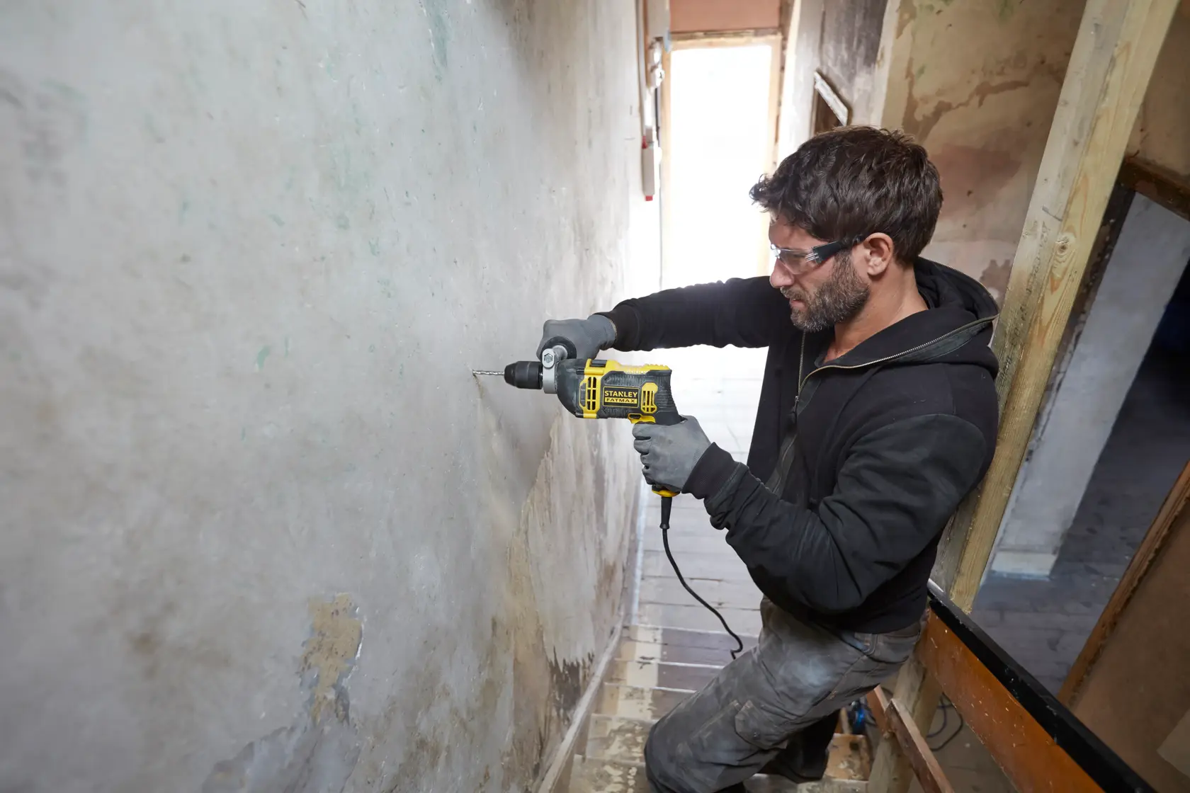 STANLEY FMEH750K corded hammer drill in use drilling into wall, product photography, side angle.