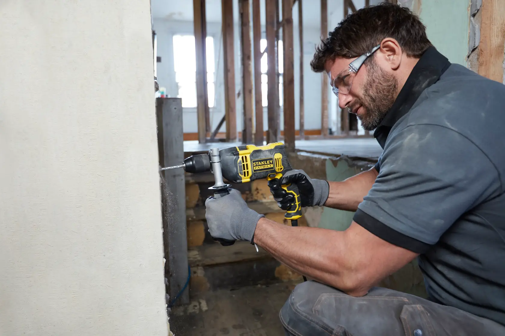 Photo of worker using STANLEY FMEH750K corded hammer drill to drill into concrete wall at construction site.