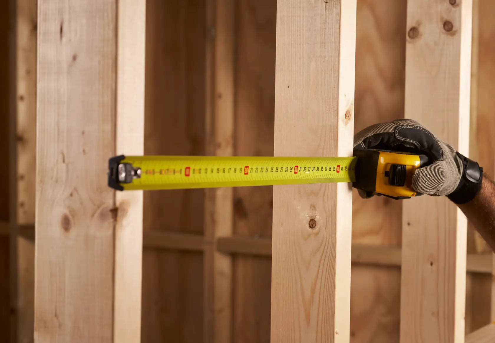 STANLEY FMHT0-33868 mètre ruban utilisé pour mesurer des montants en bois, gros plan, contexte de construction.