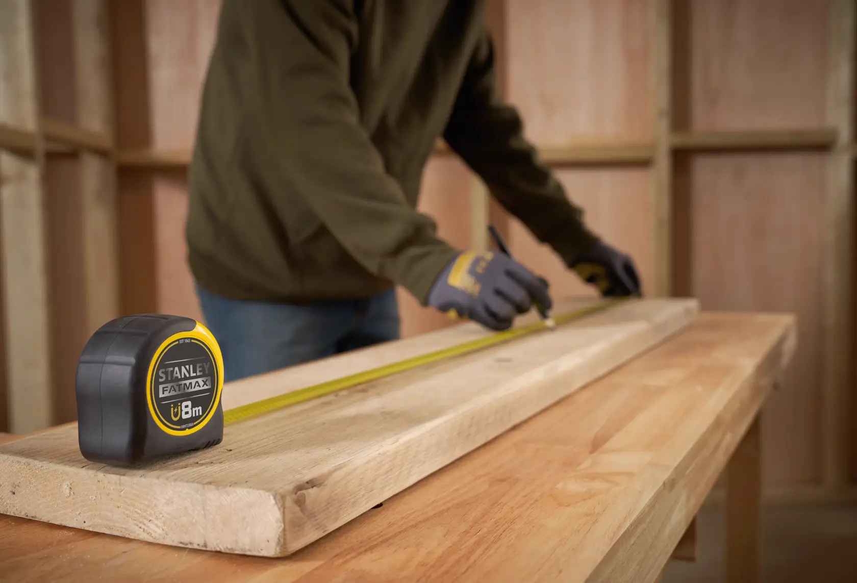 STANLEY FMHT0-33868 FATMAX mètre ruban sur poutre en bois dans atelier, personne marque mesures.