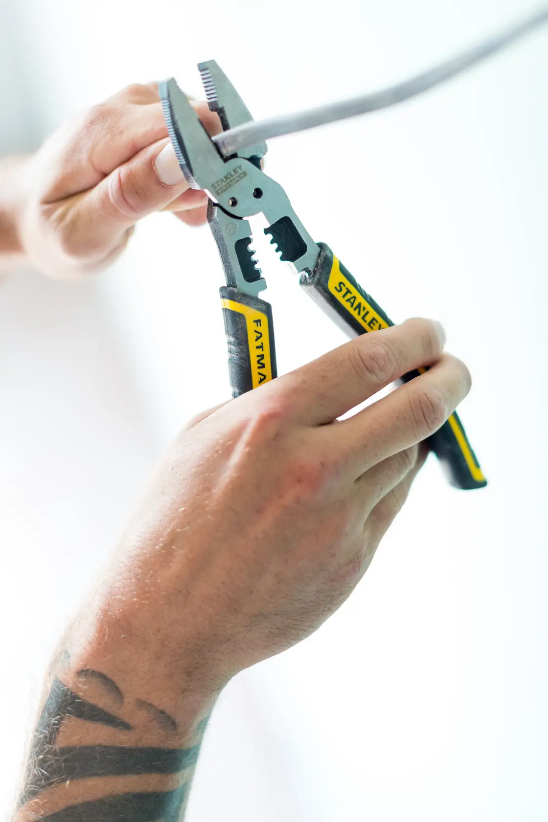 Photo de pince STANLEY FMHT0-75469 poignée jaune-noir coupant un fil, gros plan en utilisation.