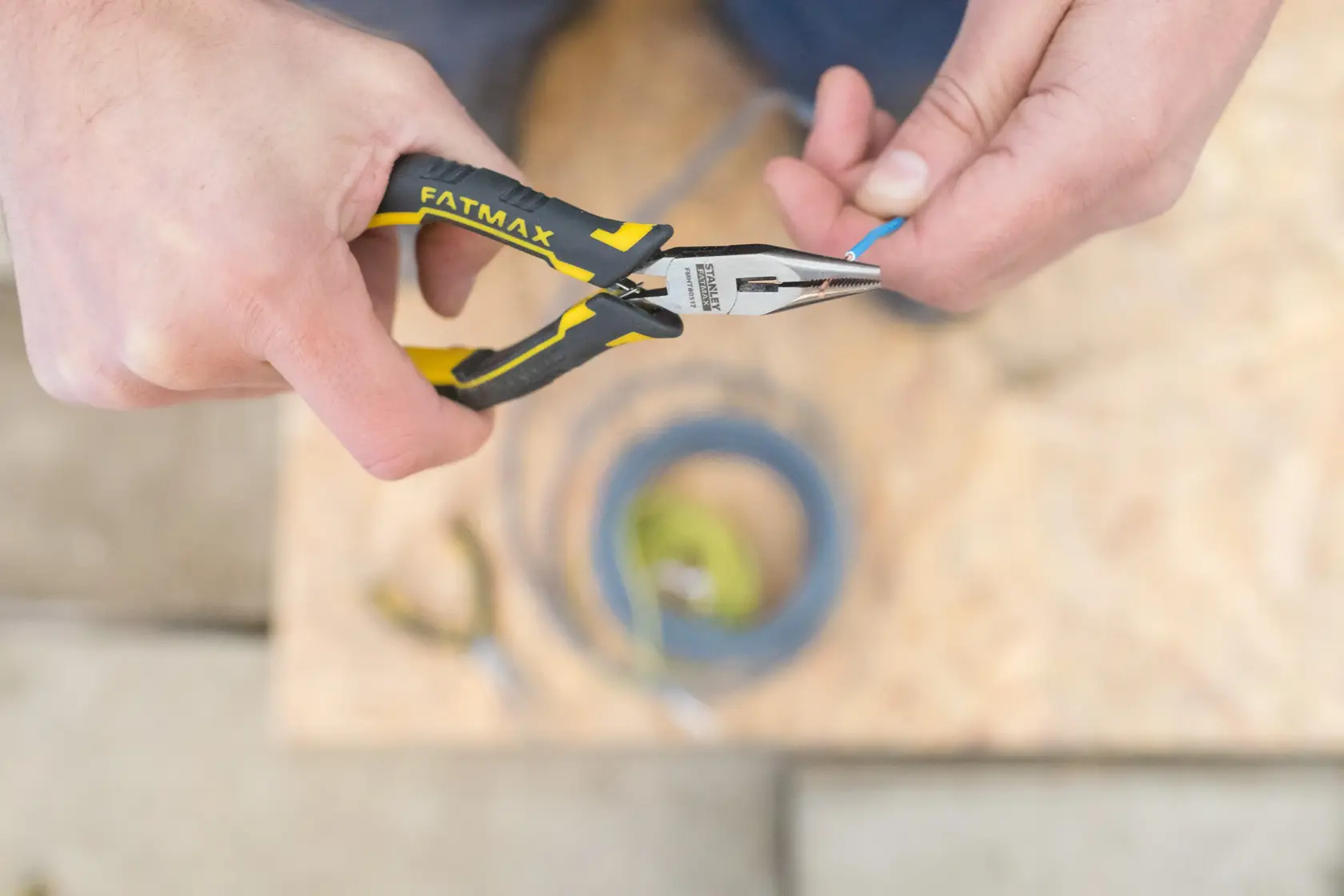 Pince à bec long STANLEY FMHT0-80517 avec poignée jaune-noir utilisée pour saisir un fil bleu.