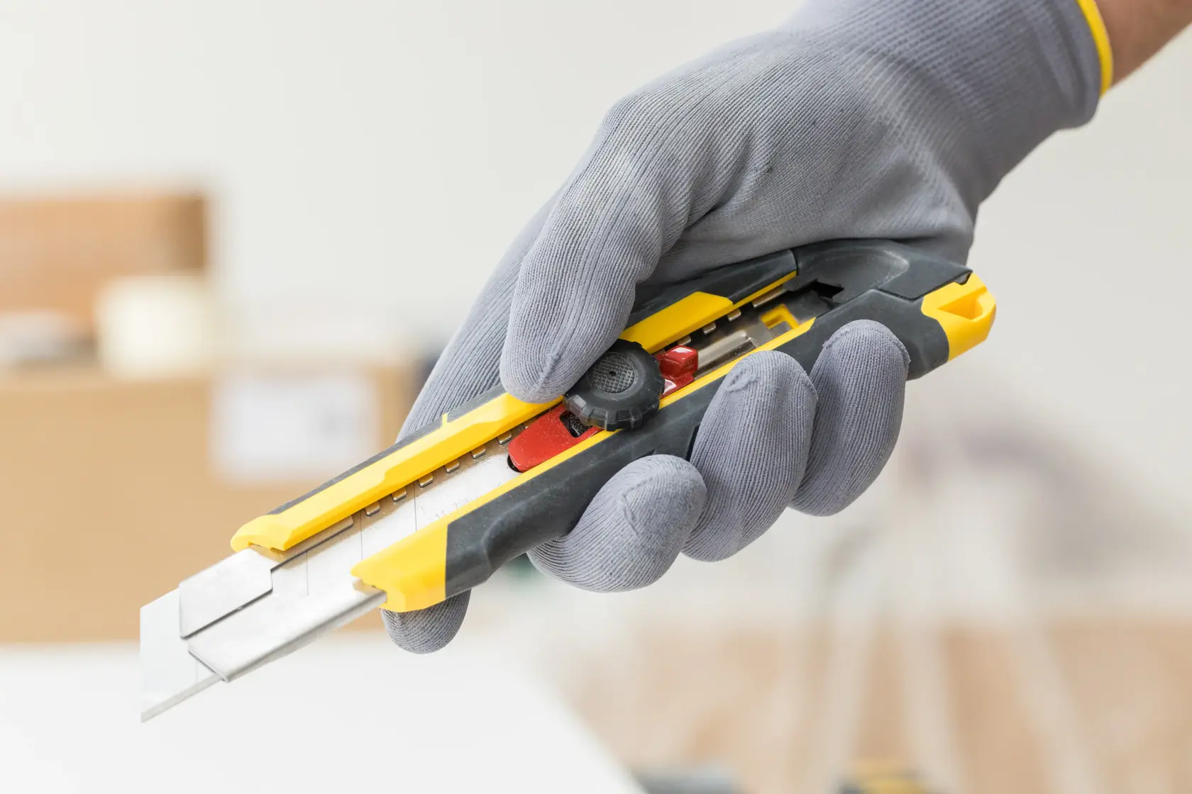 STANLEY FMHT10330-0 utility knife with yellow and black body, held in a gloved hand.