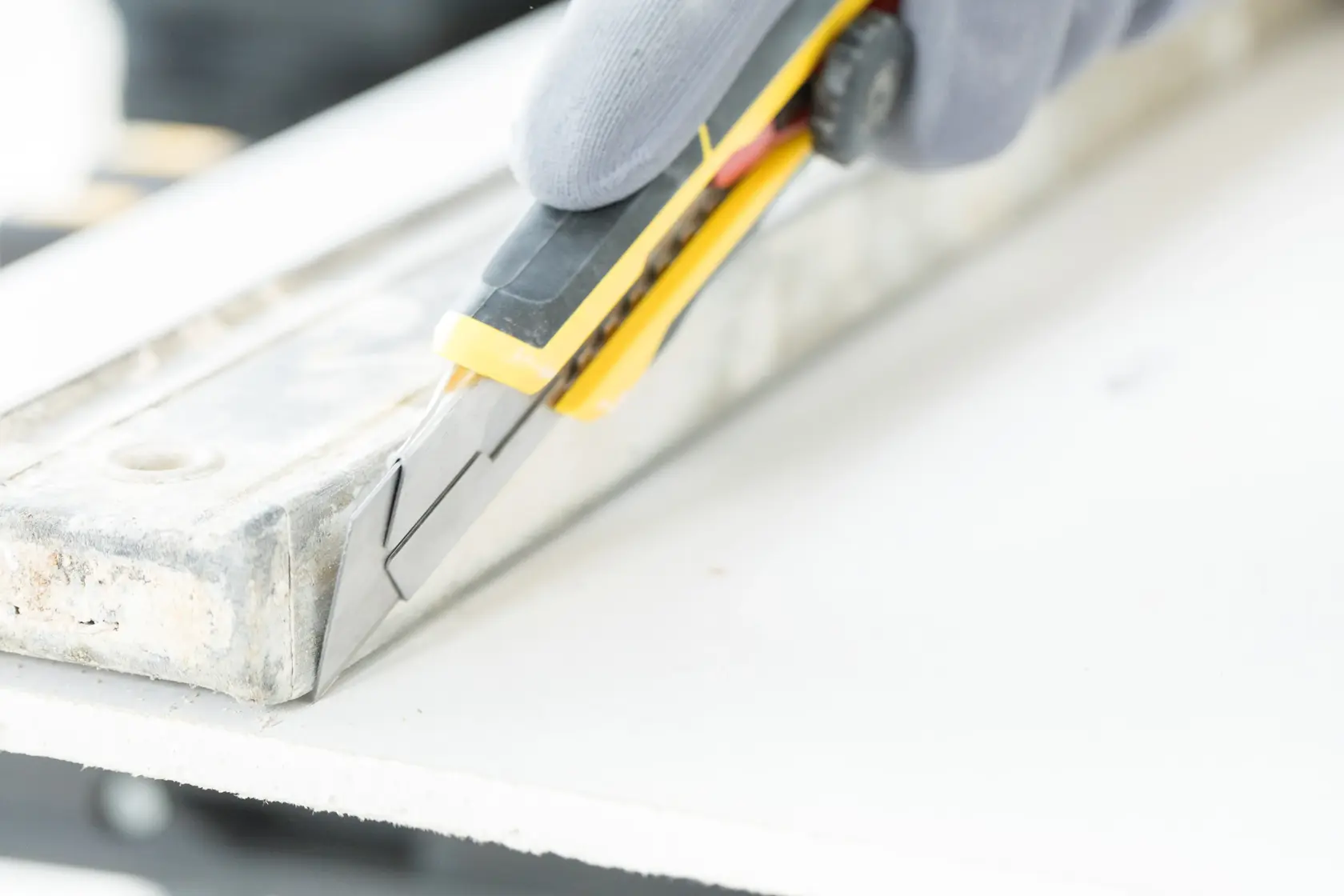 STANLEY FMHT10330-0 utility knife cutting drywall, close-up photo showing blade and yellow handle.