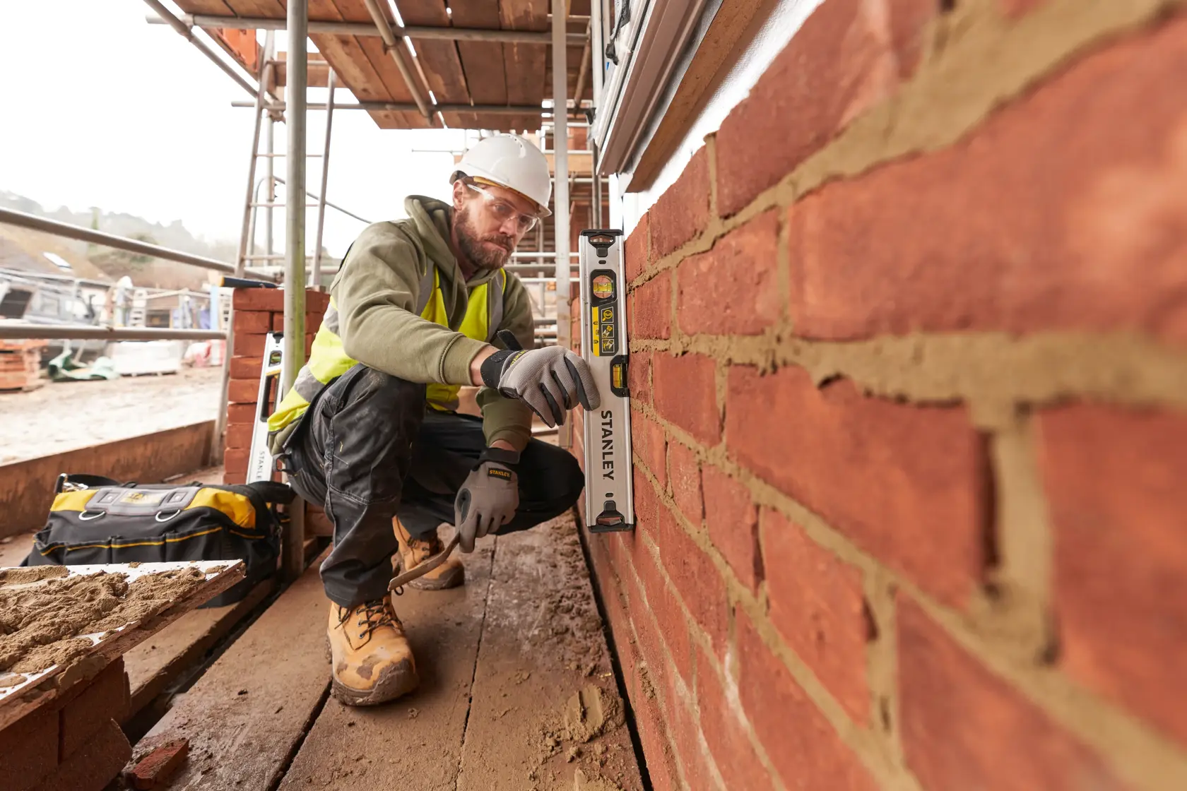 STANLEY FMHT43670-1 spirit level used by construction worker checking vertical alignment of brick wall on site.