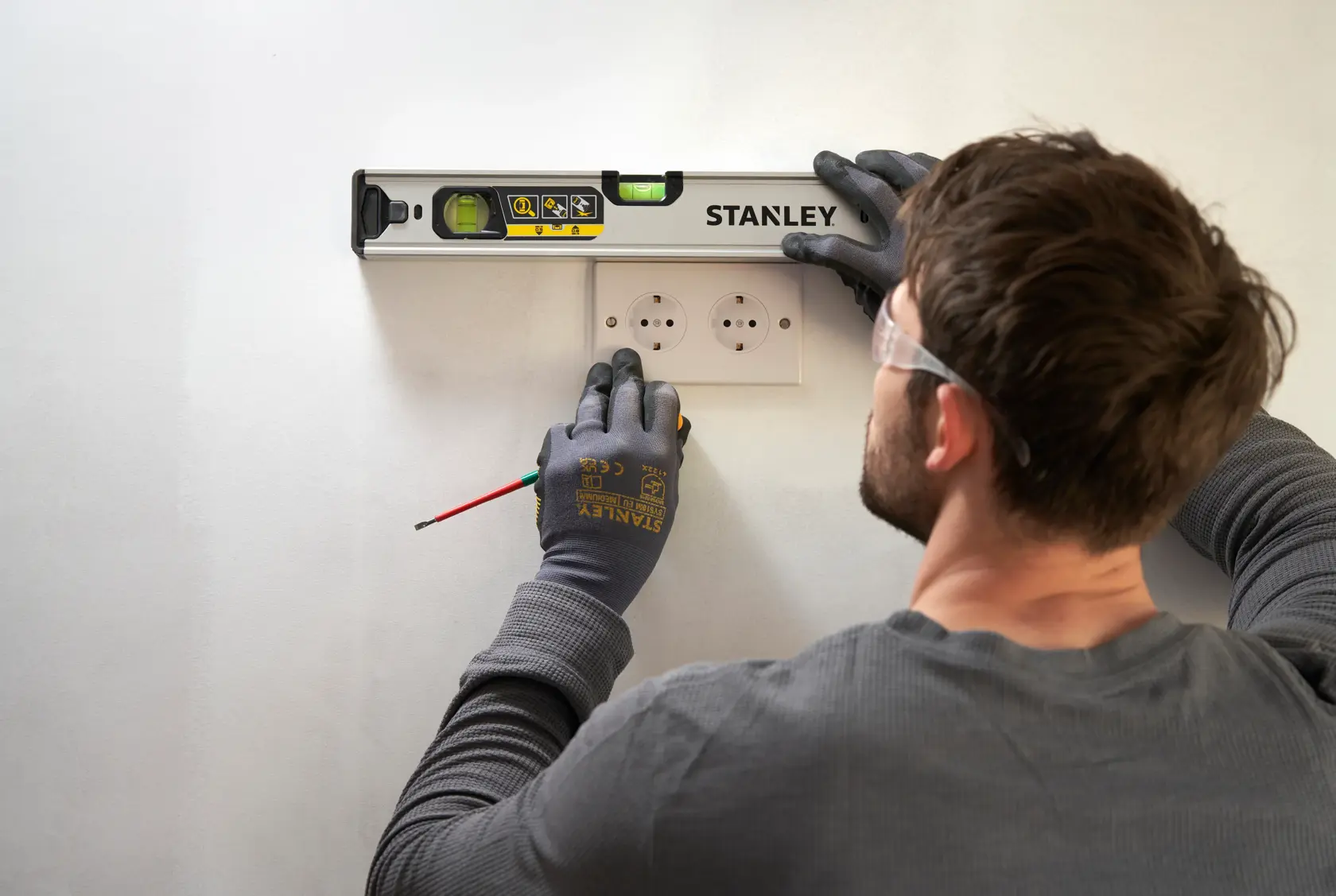 STANLEY FMHT43670-1 spirit level used by a person marking wall above electrical sockets, angled top view.