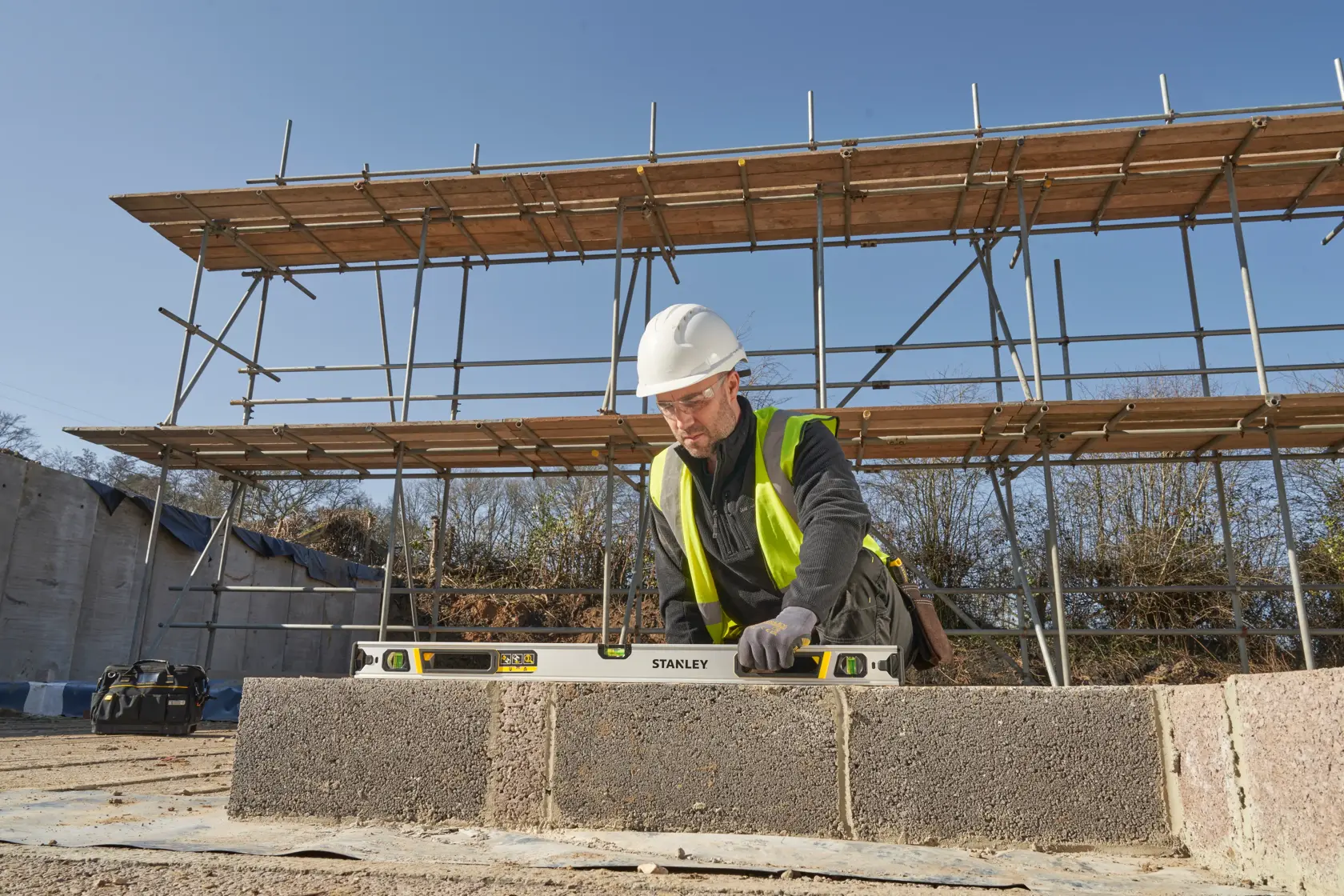 STANLEY FMHT43674-1 spirit level used by a worker on a construction site, photographed outdoors.