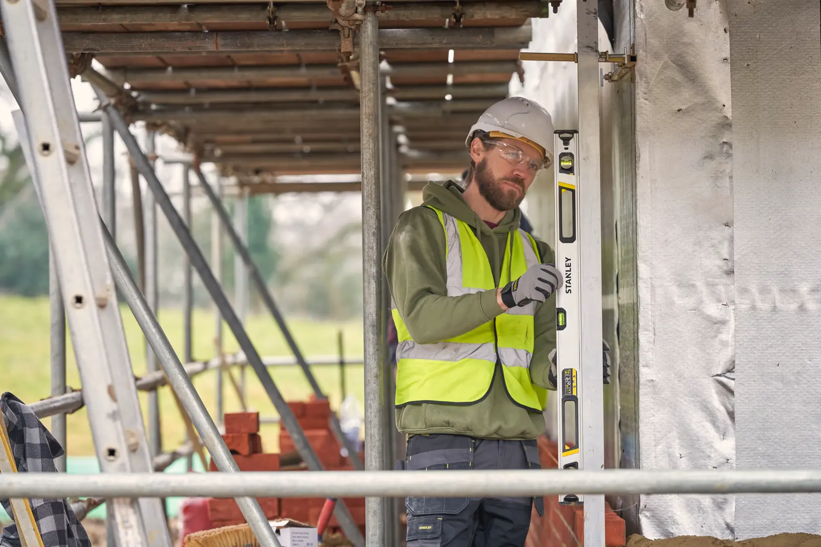 STANLEY FMHT43675-1 spirit level used vertically on a construction site by a worker in a safety vest.