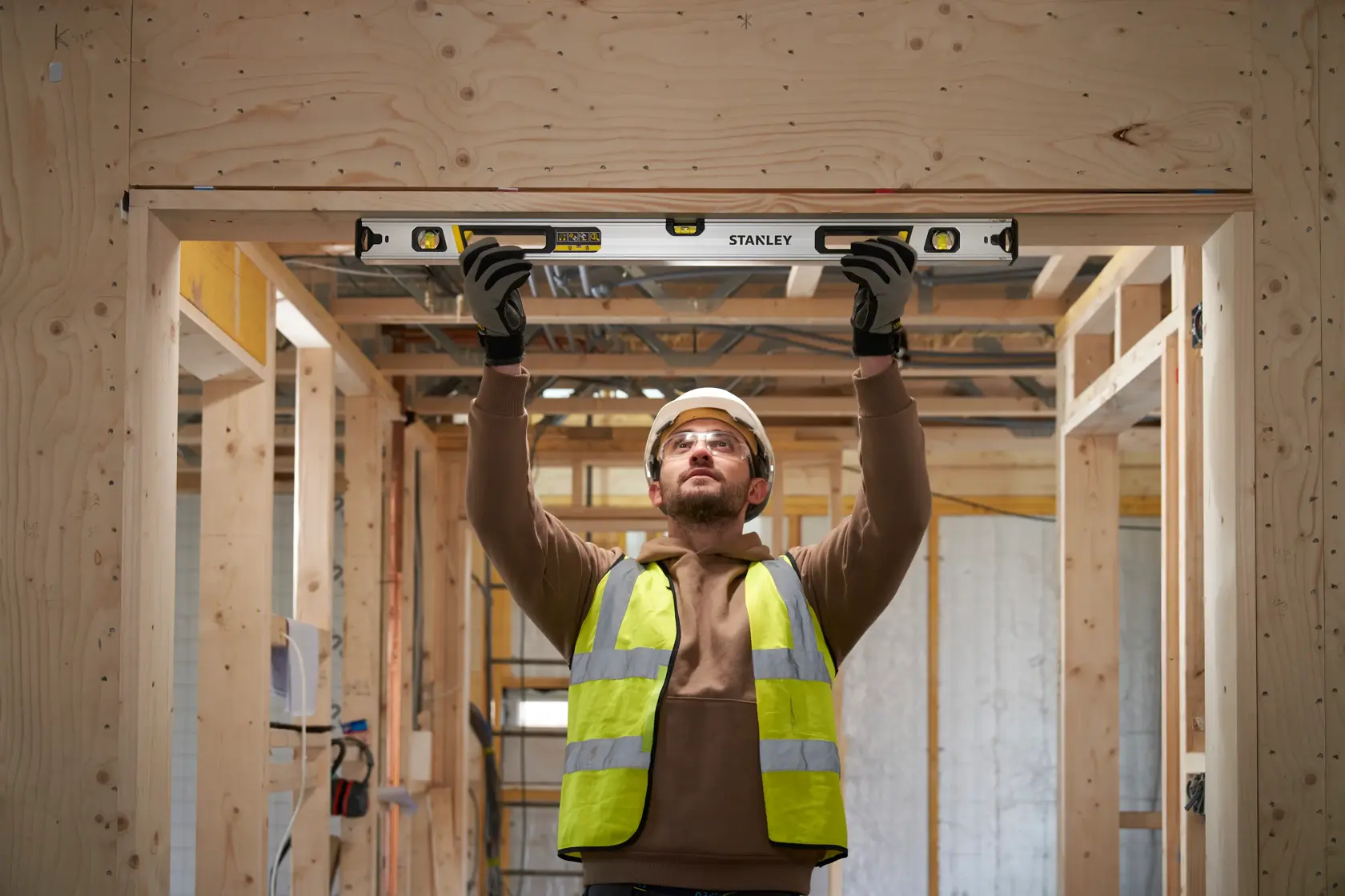 Photo of STANLEY FMHT43675-1 spirit level in use on a wooden door frame during construction.