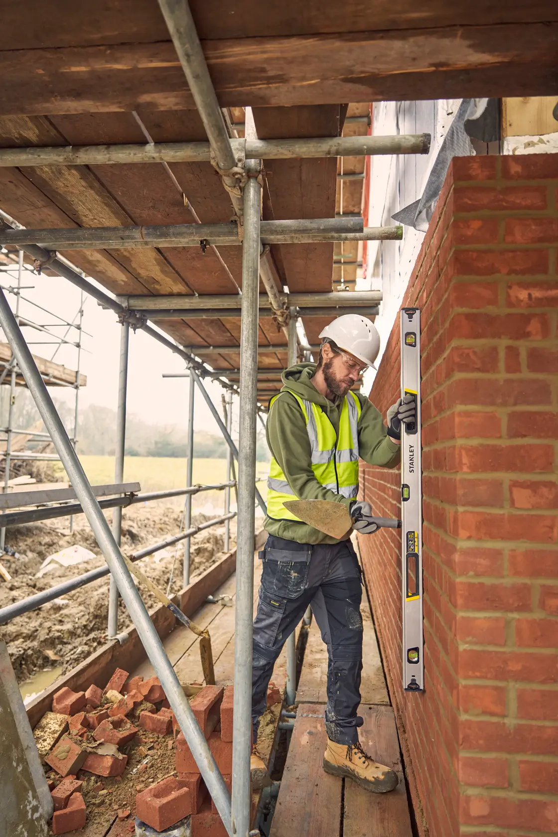 STANLEY FMHT43676-1 spirit level used by a construction worker to check a brick wall on scaffolding.
