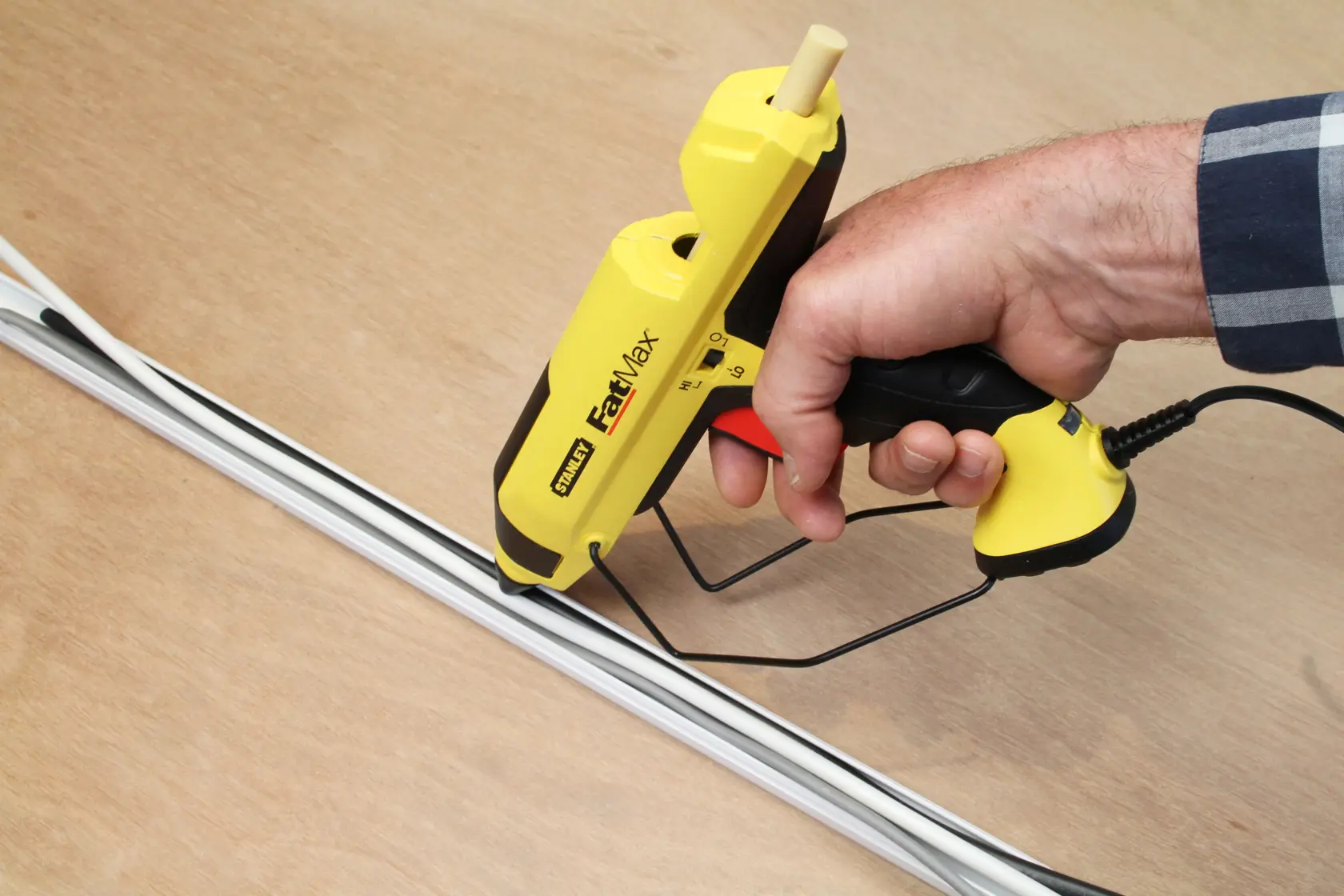 Stanley FatMax yellow glue gun with black and red accents and a metal stand, shown on a white background.