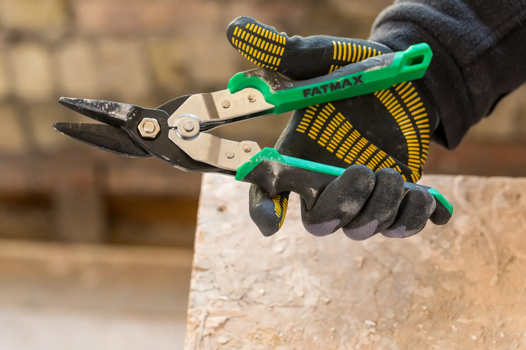 STANLEY FMHT73557-0 green handle aviation snips held in a gloved hand, close-up photo.