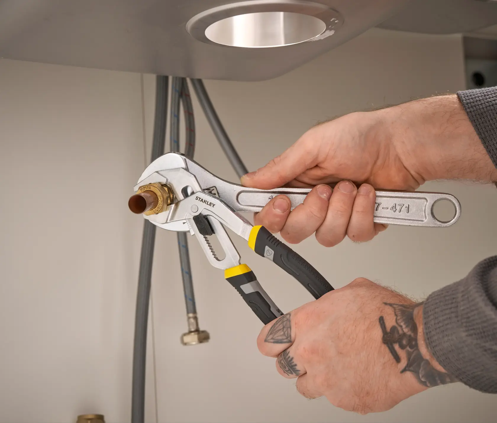Photo of STANLEY FMHT75502-0 slip joint pliers being used to grip a pipe fitting under a sink.