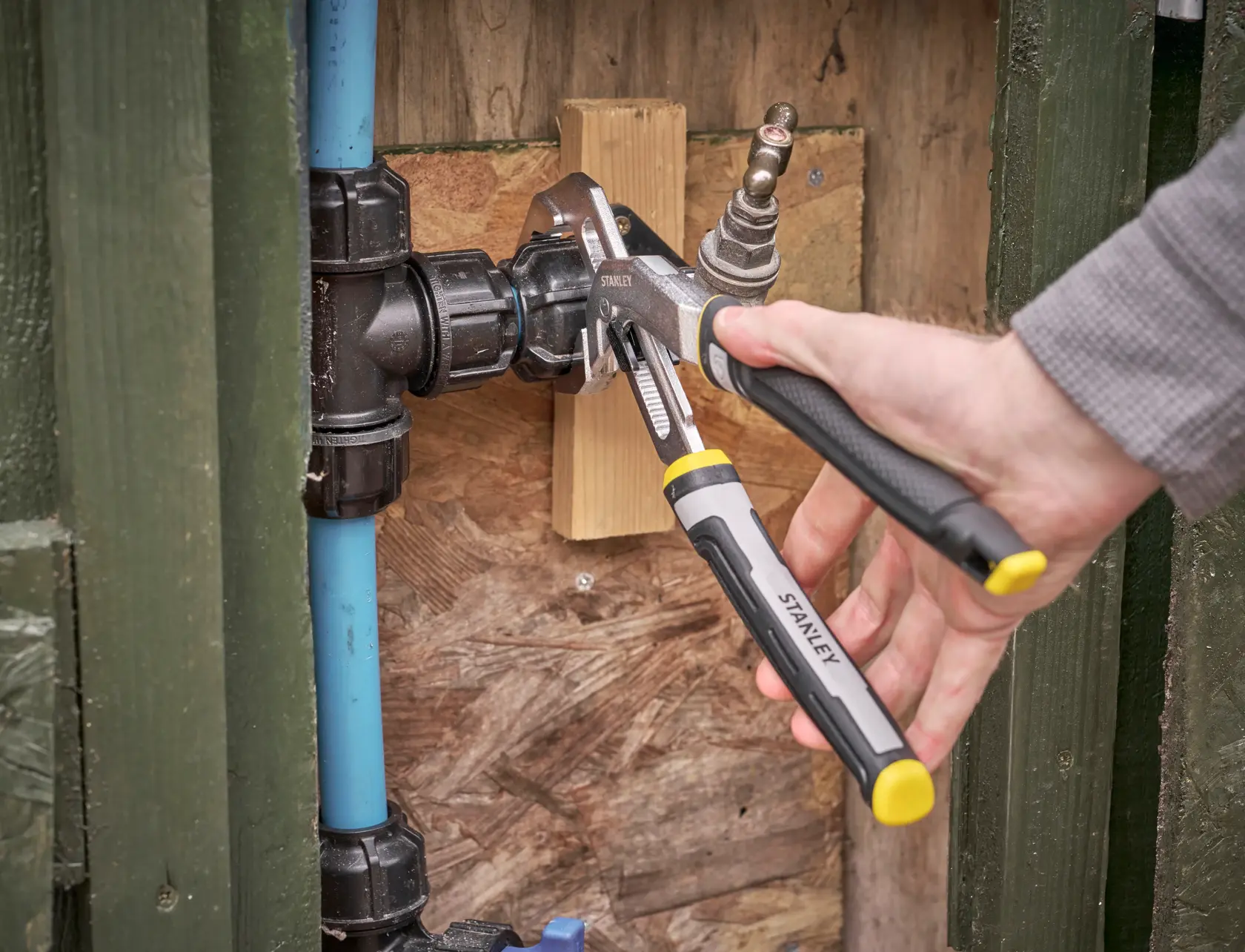 Photo de la pince réglable STANLEY FMHT75512-0 utilisée sur un raccord de plomberie, gros plan lors de l'installation.