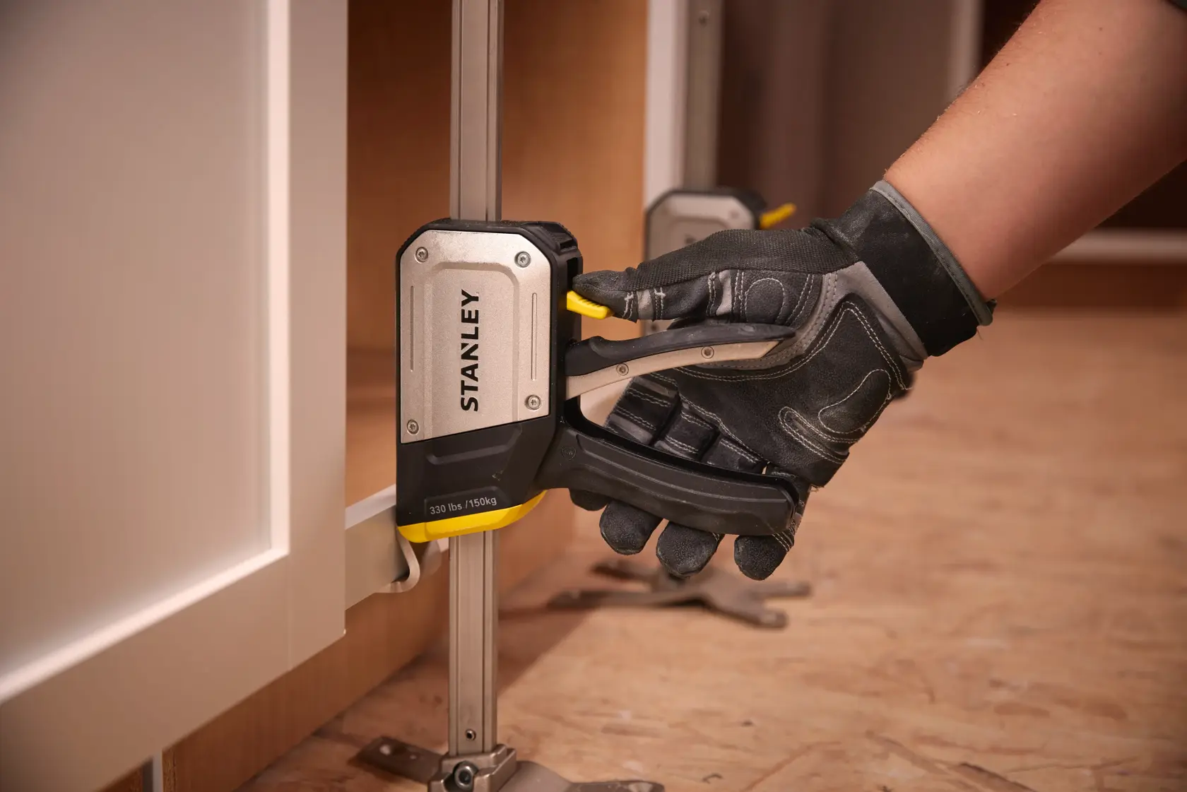 STANLEY FMHT83550-1 cabinet clamp in use, close-up angle, black and silver tool with yellow lever.