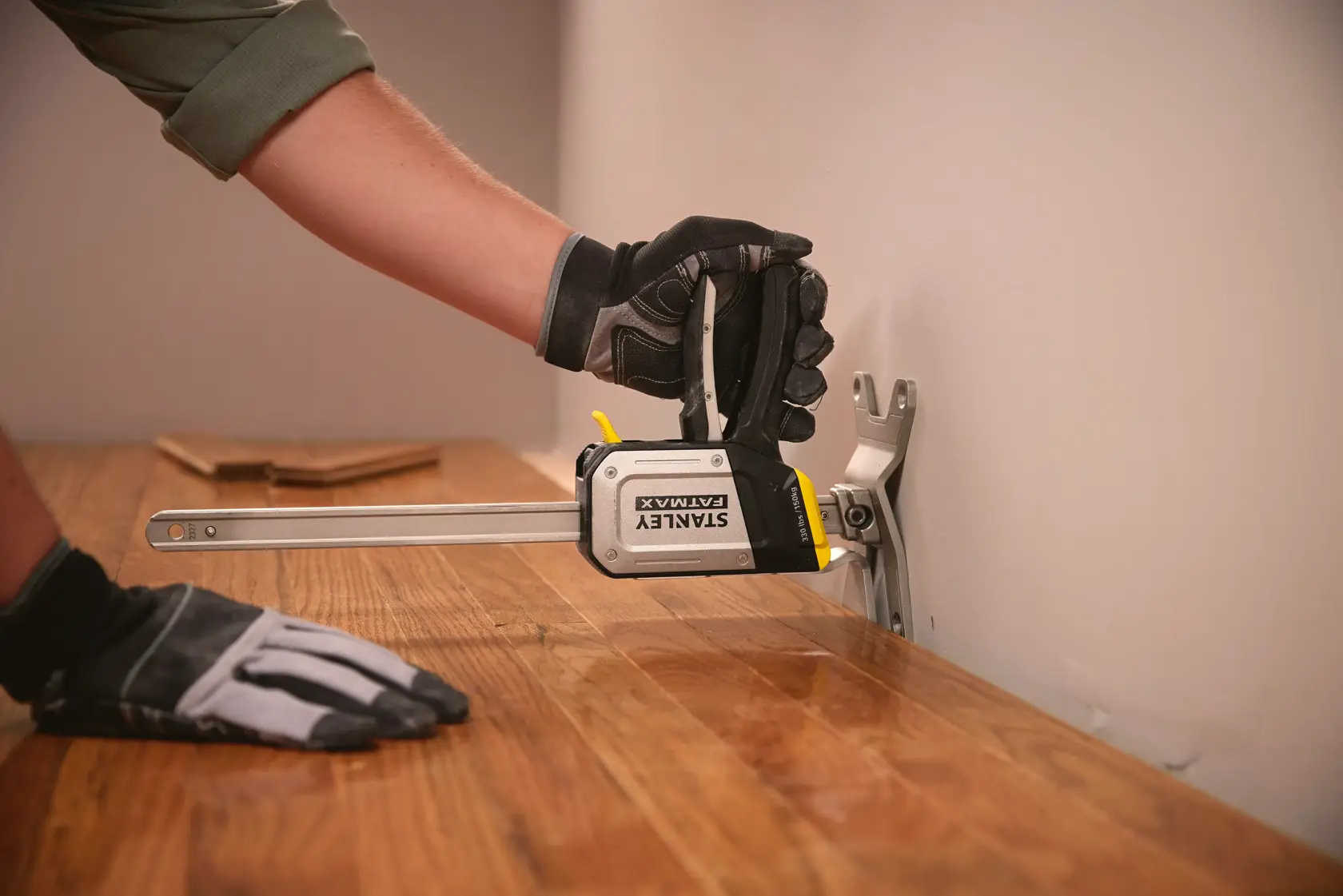 Photo of STANLEY FMHT83550-1 clamp holding wood flooring in place during installation.