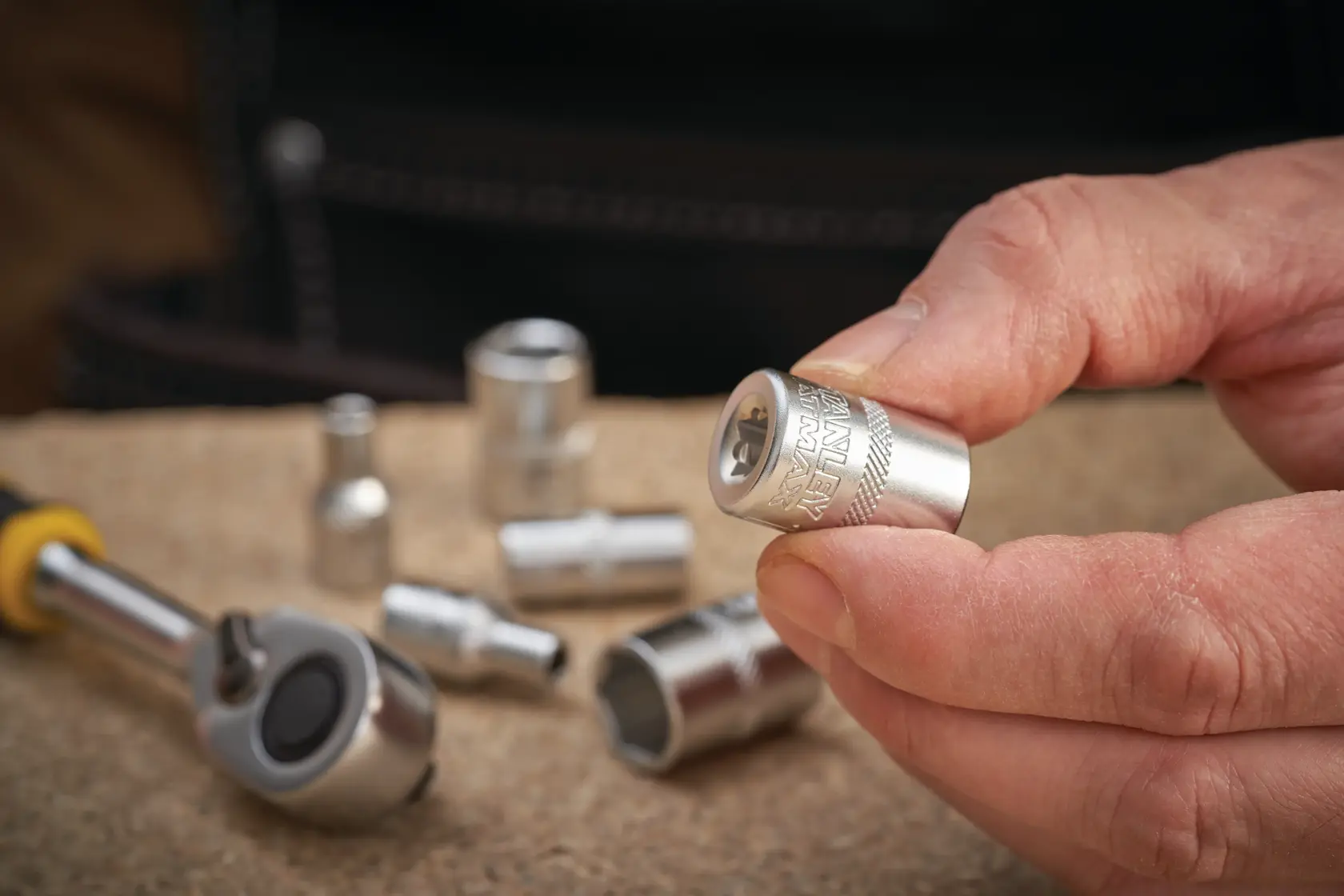 Photo of STANLEY FMMT17185-0 socket held in hand, with ratchet and other sockets on work surface.