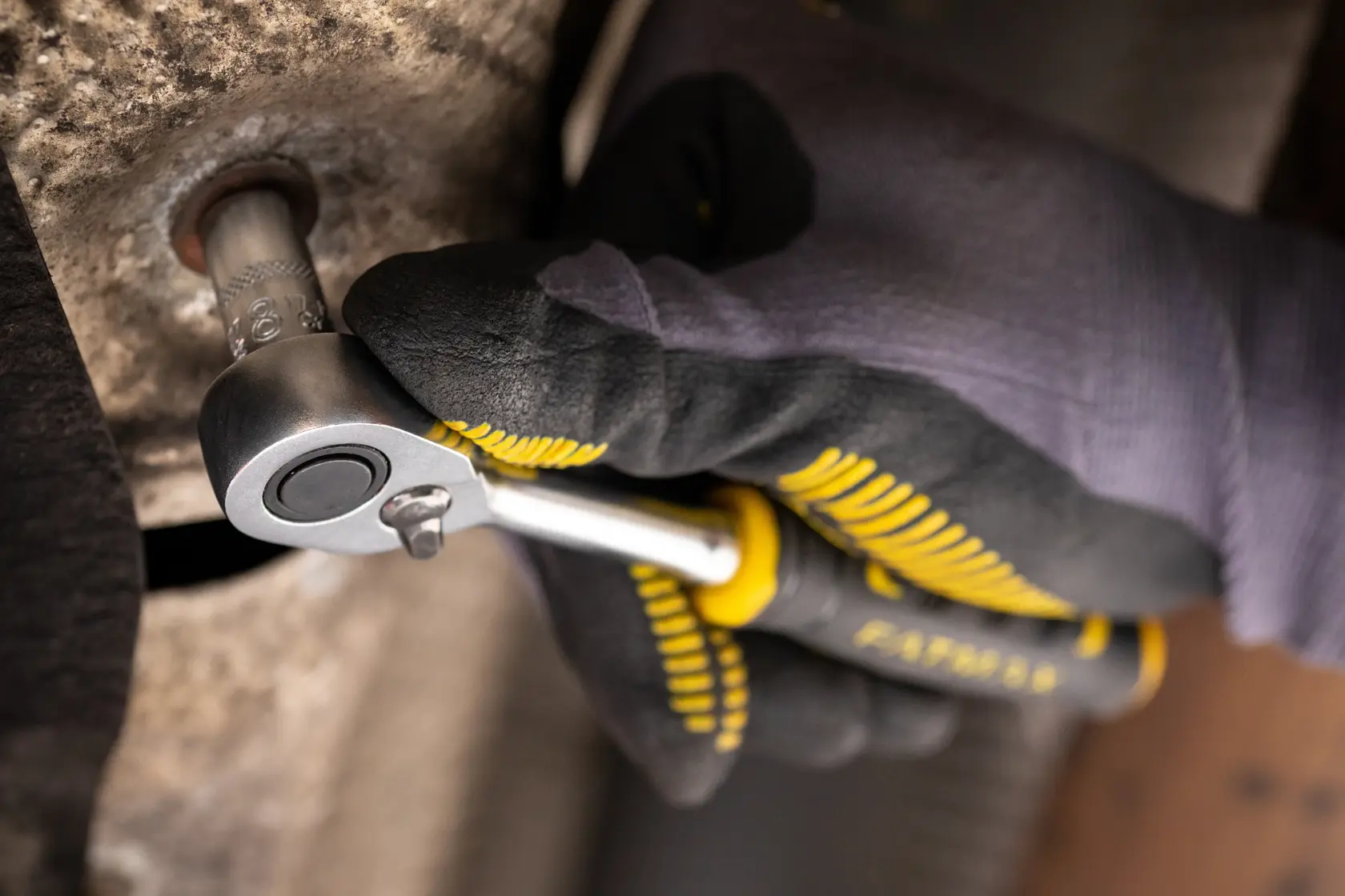 Photo of STANLEY FMMT17186-0 ratchet wrench in use, held by gloved hand, tightening a bolt.