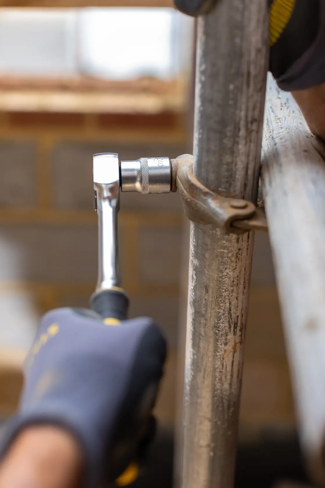 STANLEY FMMT17209-0 ratchet wrench used on metal pipe, close-up with gloved hand, photography category.