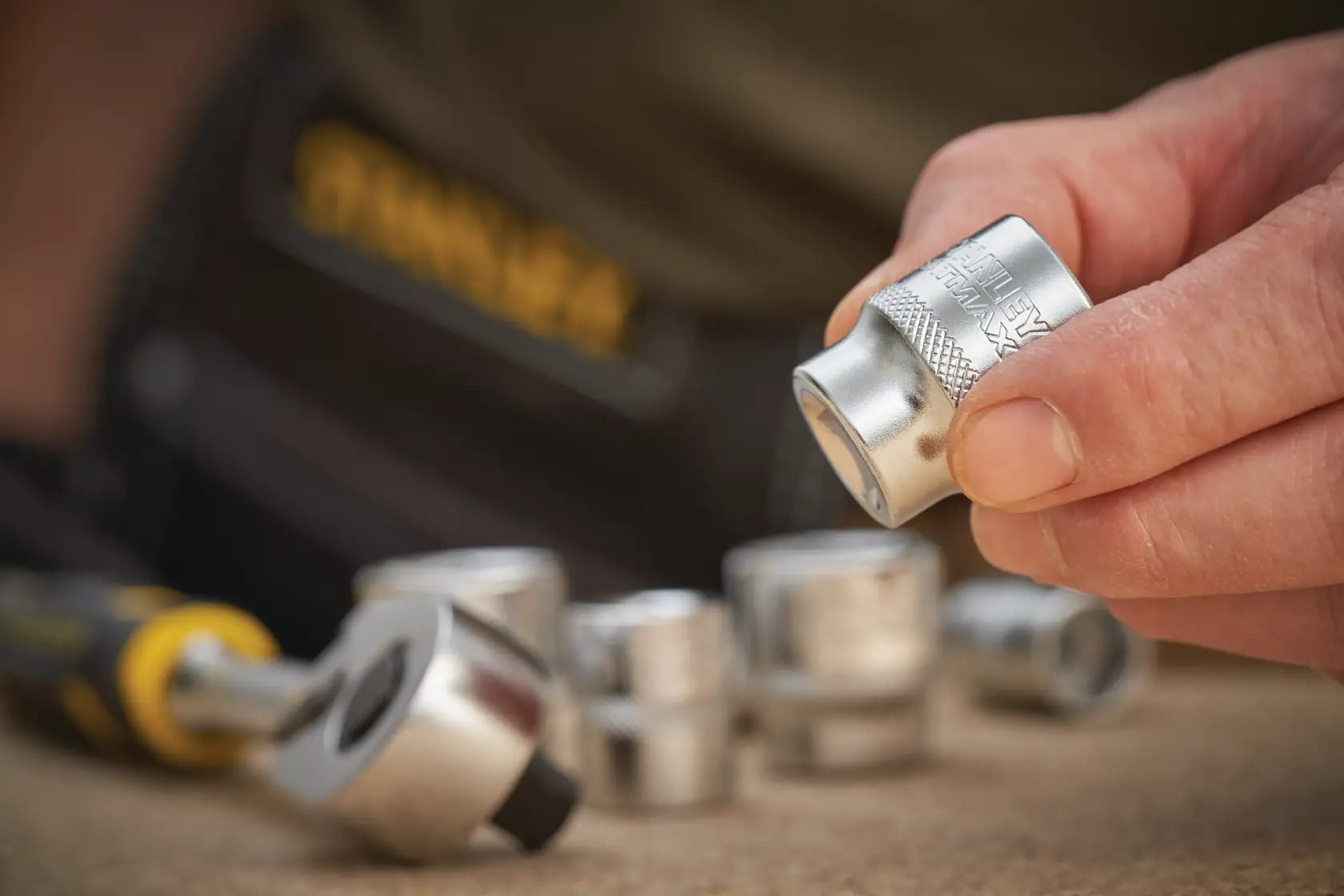 STANLEY FMMT17223-0 socket set with ratchet, close-up photo, silver sockets held by hand.