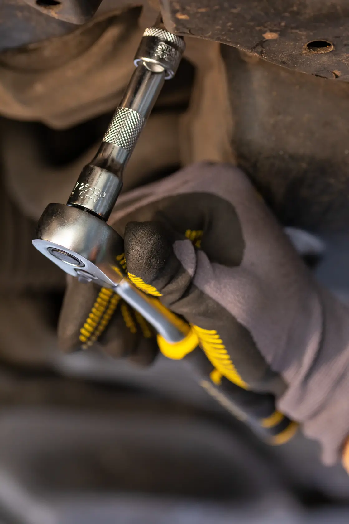 STANLEY FMMT25131-0 ratchet wrench used by a gloved hand for automotive repair, close-up view.